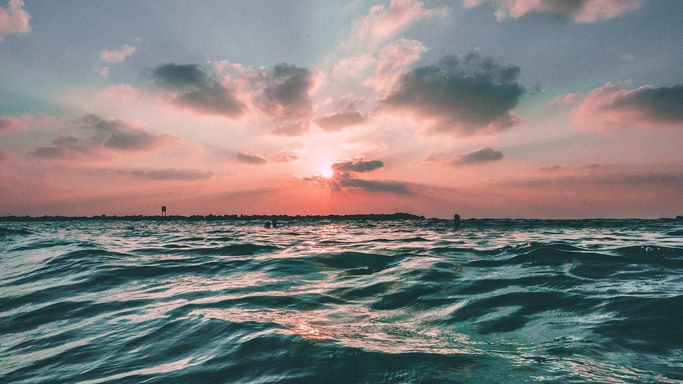 夏日美學動畫 桌布 壁紙 — 夕陽穿透粉紅雲層，照耀在紋理豐富的藍綠色海洋上，地平線上有遠處的剪影。