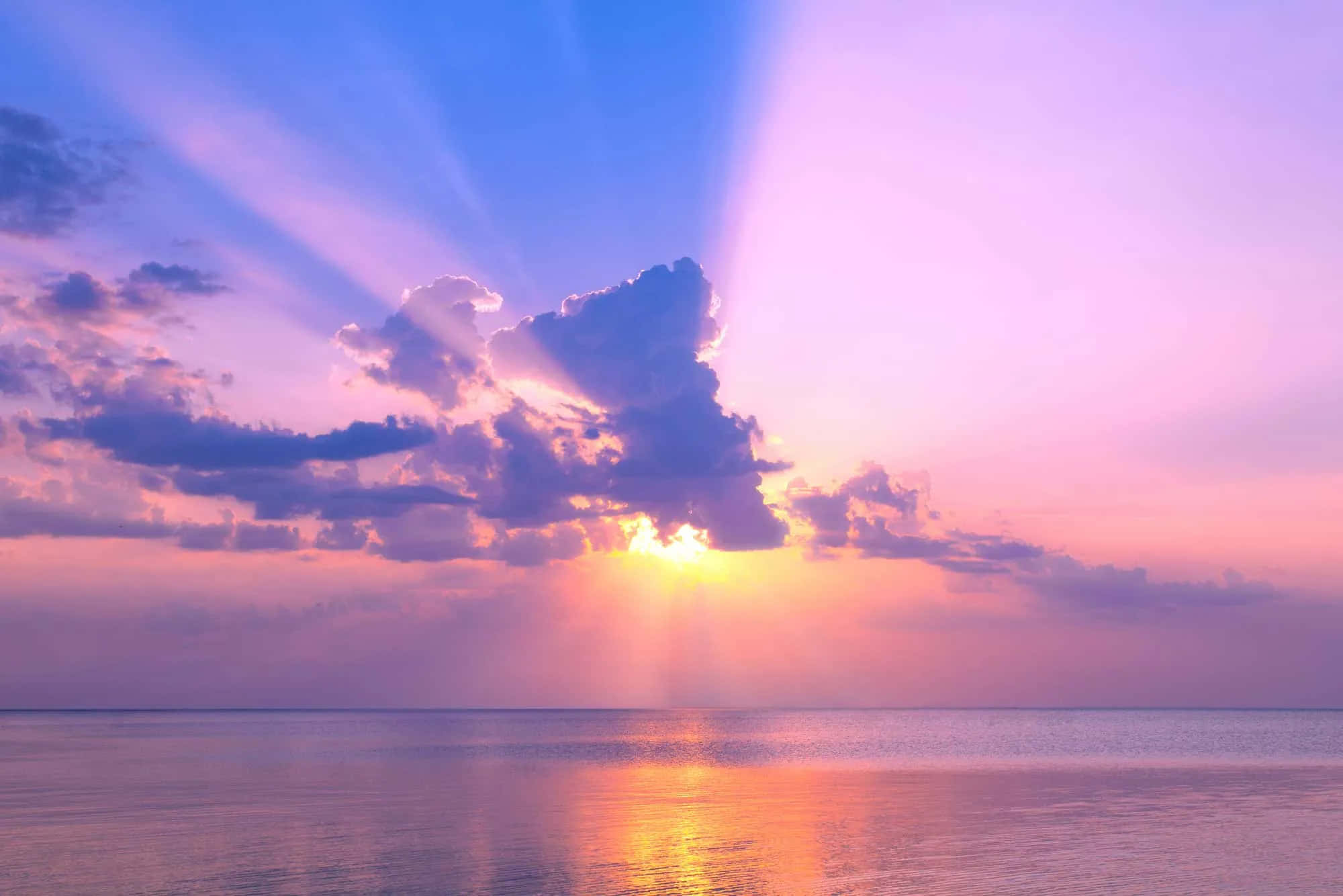 Colorful Sky 桌布 壁紙 — 夕陽穿透紫色雲層，在平靜的海面上投下金色倒影。