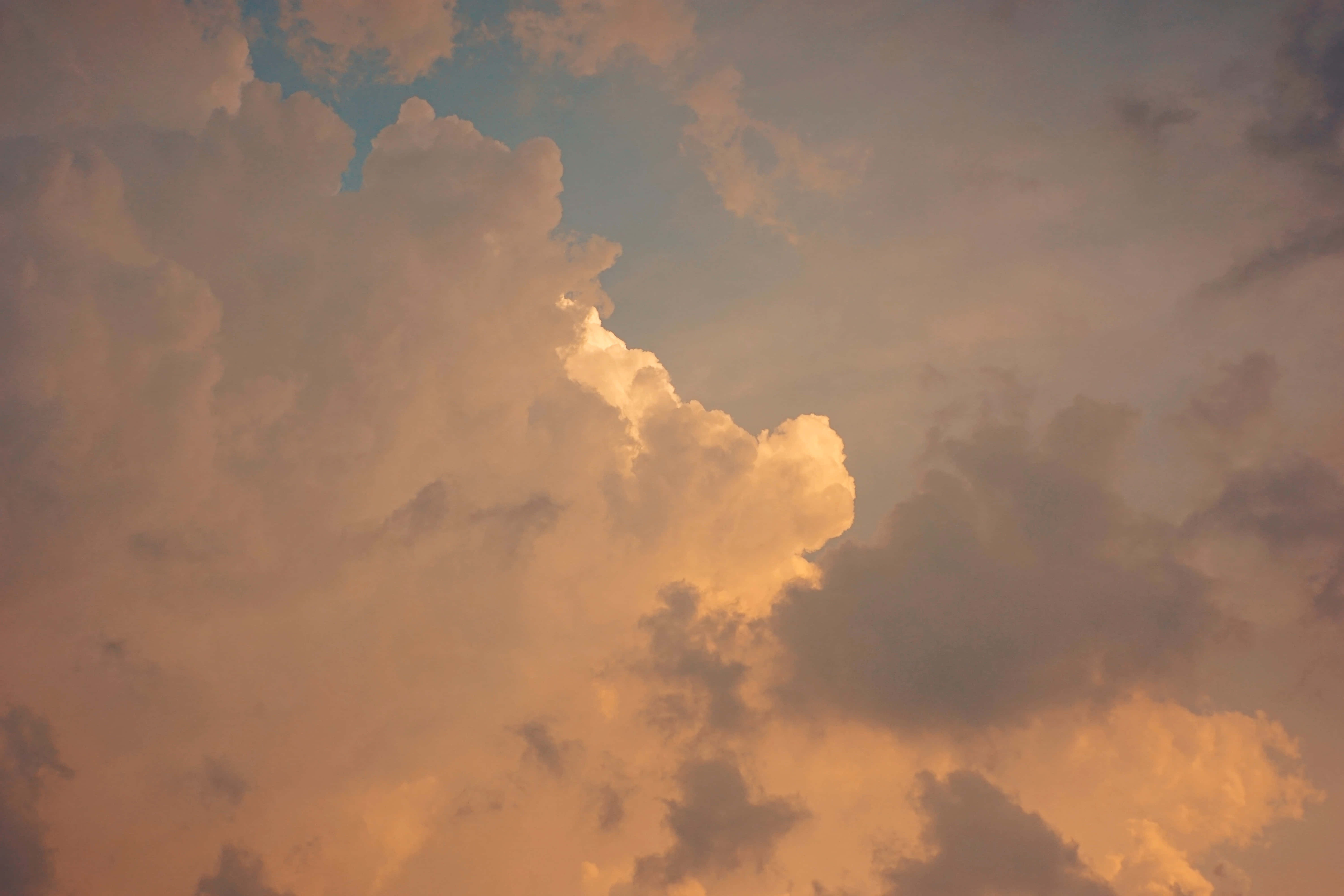 美學雲朵 桌布 壁紙 — 夕陽穿透雲層時，豐厚的雲朵散發出溫暖的琥珀色和柔和的藍色光芒。
