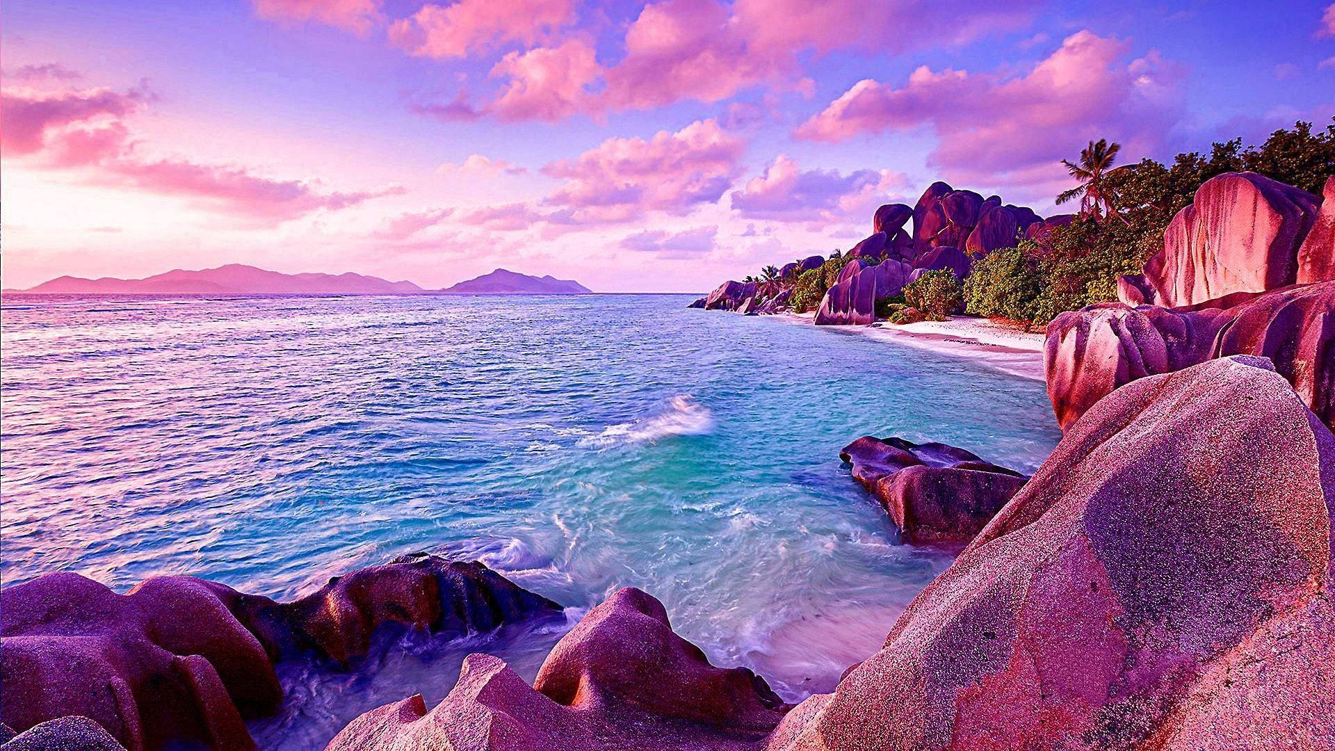 海灘 桌布 壁紙 — 夕陽西下，在拍打著巨大花崗岩巨石和白色沙灘的碧綠海水上，繪出粉紅色和紫色的雲彩。