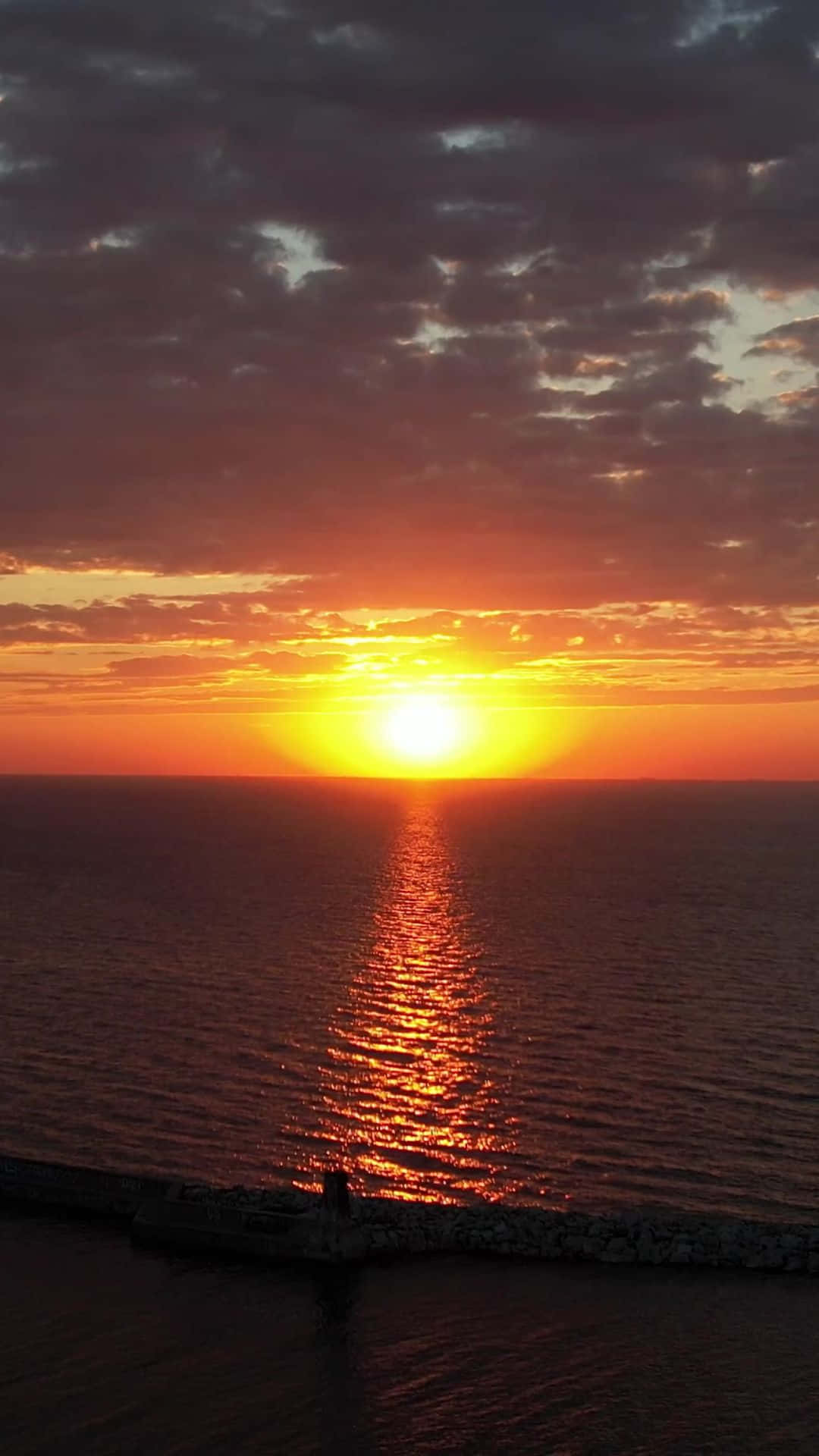 sun set 壁紙 — 夕陽西下，在海洋上投射出火熱的橙色和金色色調，太陽沉入地平線以下。