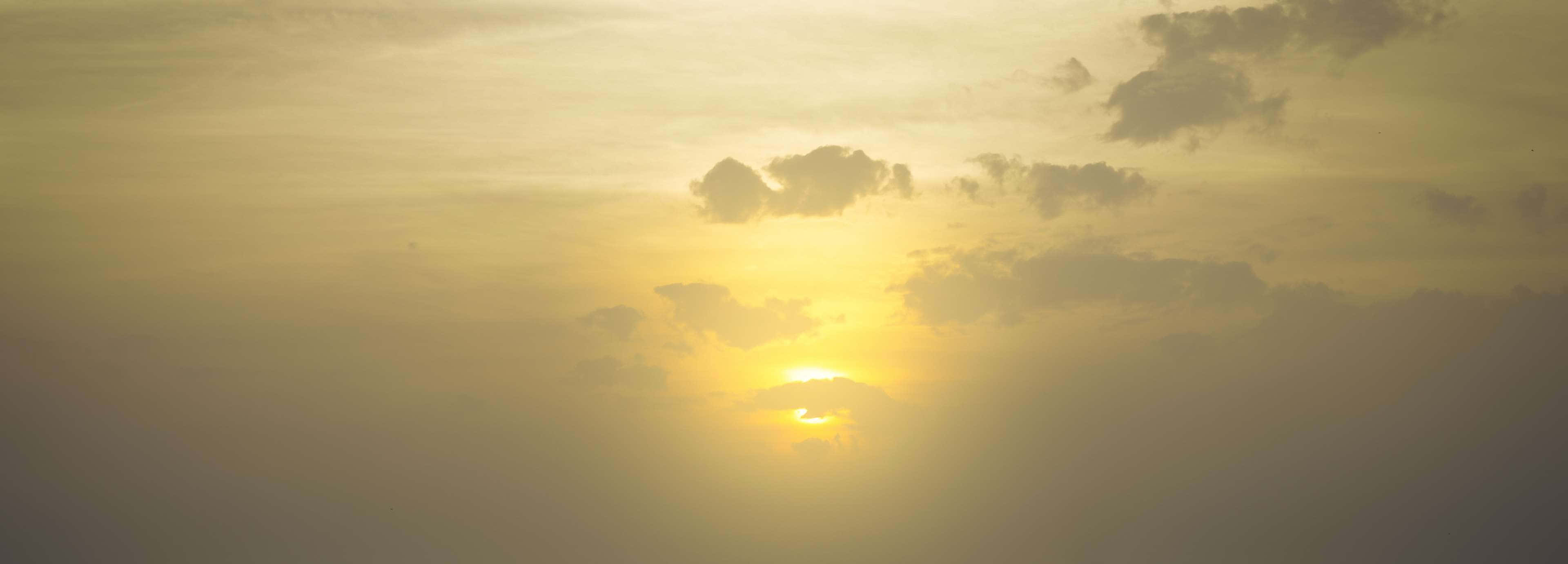 Yellow Sky 桌布 壁紙 — 夕陽西下，燦爛的太陽穿過散落的雲層，溫暖地照耀在金色的天空中。