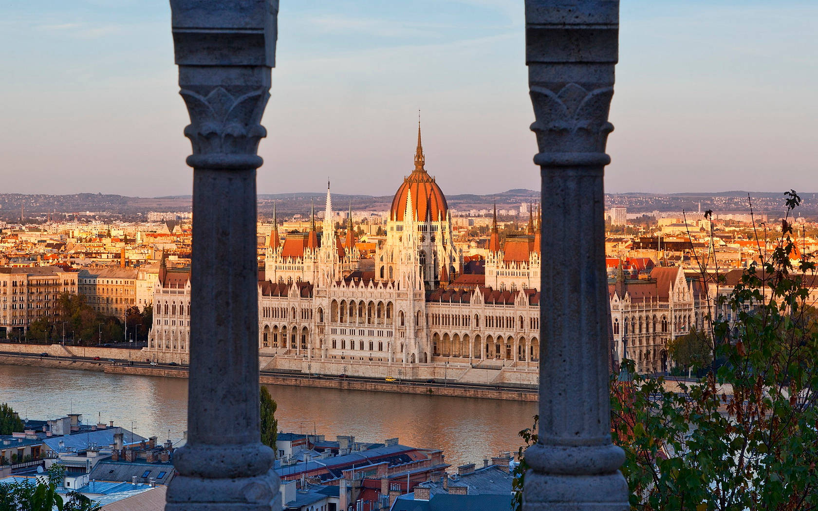 Hungary 桌布 壁紙 — 夕陽餘暉穿過石柱灑落在俯瞰多瑙河的布達佩斯國會大廈上。