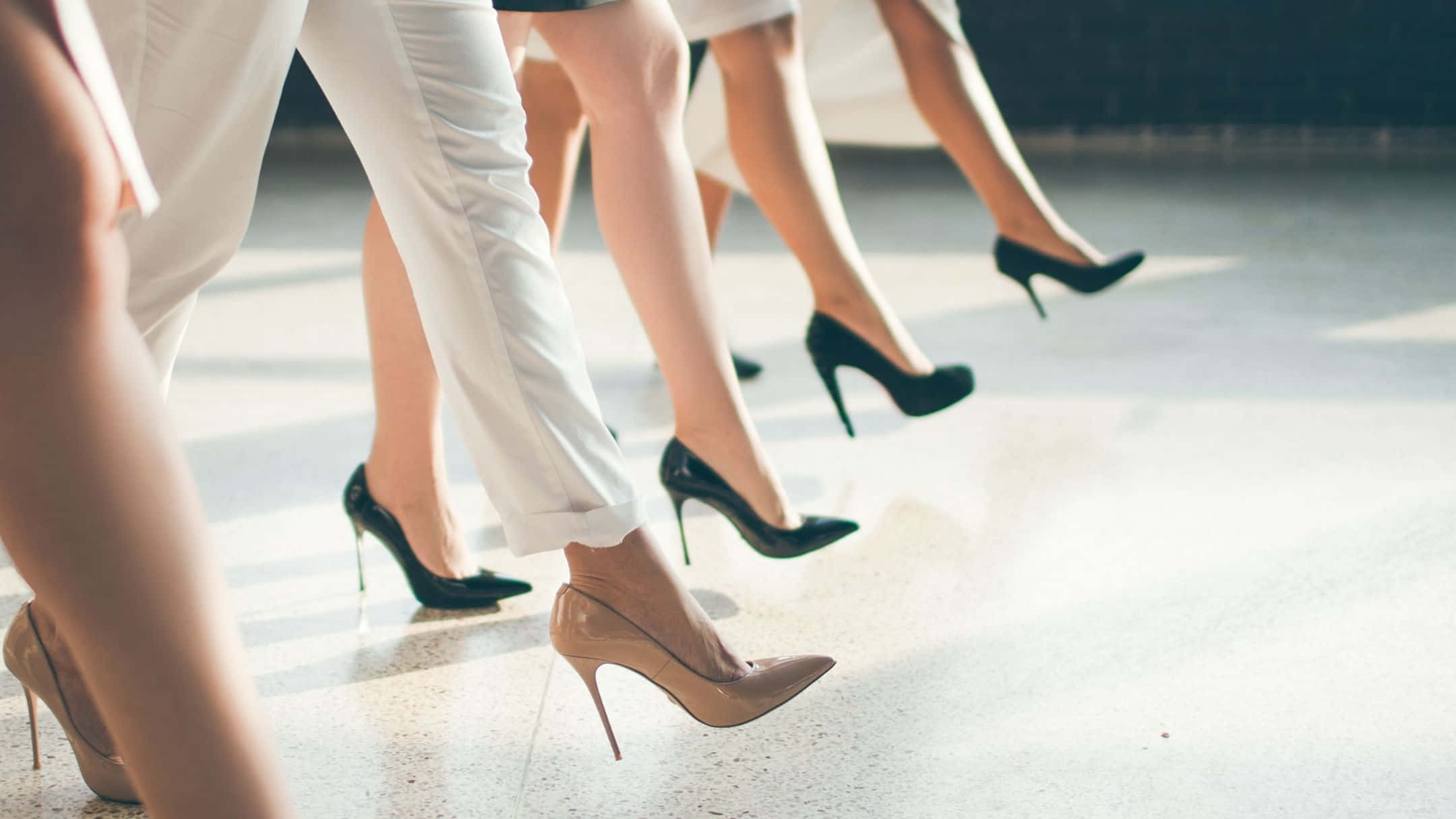 women 桌布 壁紙 — 多位女性穿著時尚高跟鞋在拋光地板上自信行走的腿部特寫。