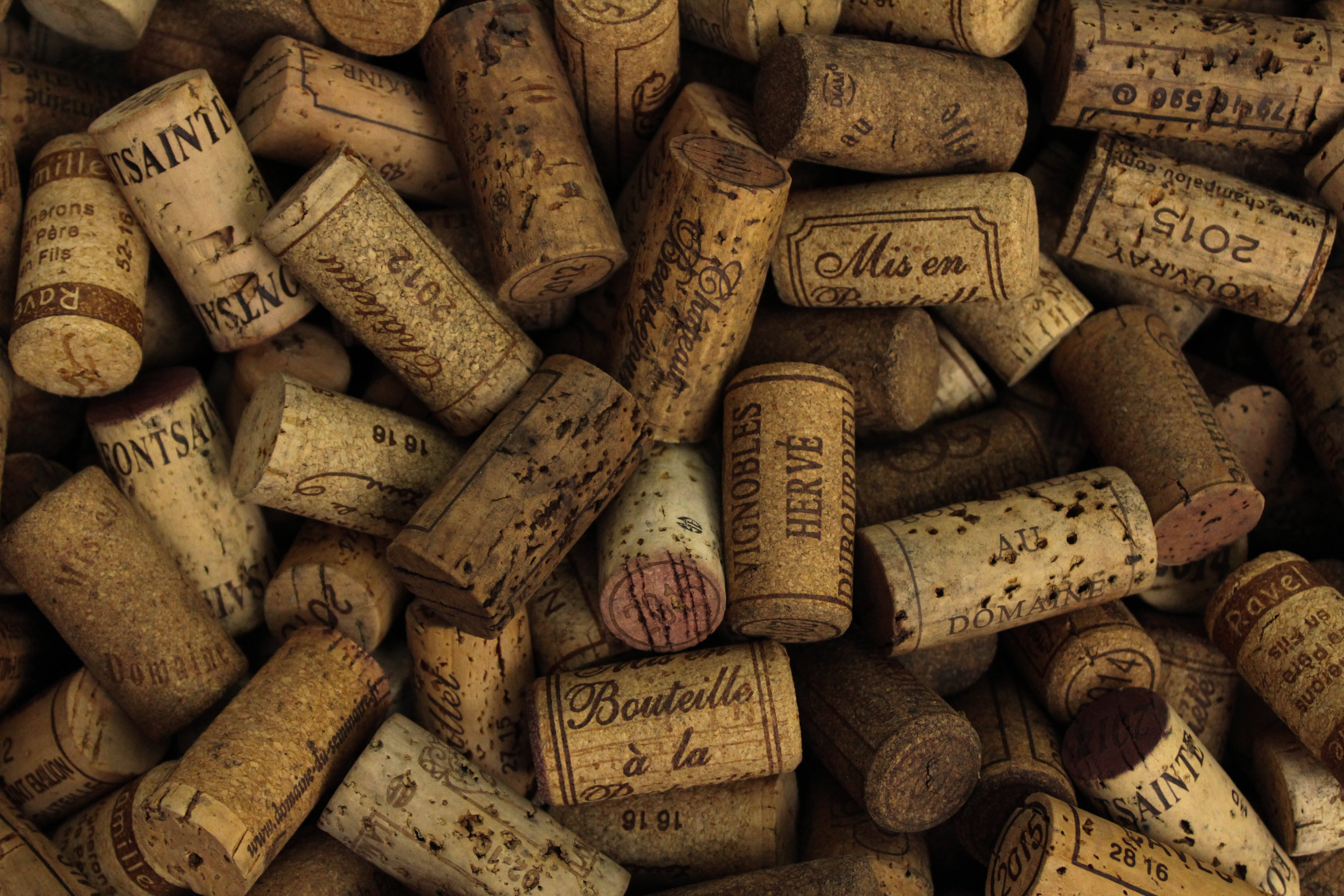 drinking wine 桌布 壁紙 — 多個帶有復古標籤和墨水印章的風化葡萄酒軟木塞堆疊在一起的近距離照片。