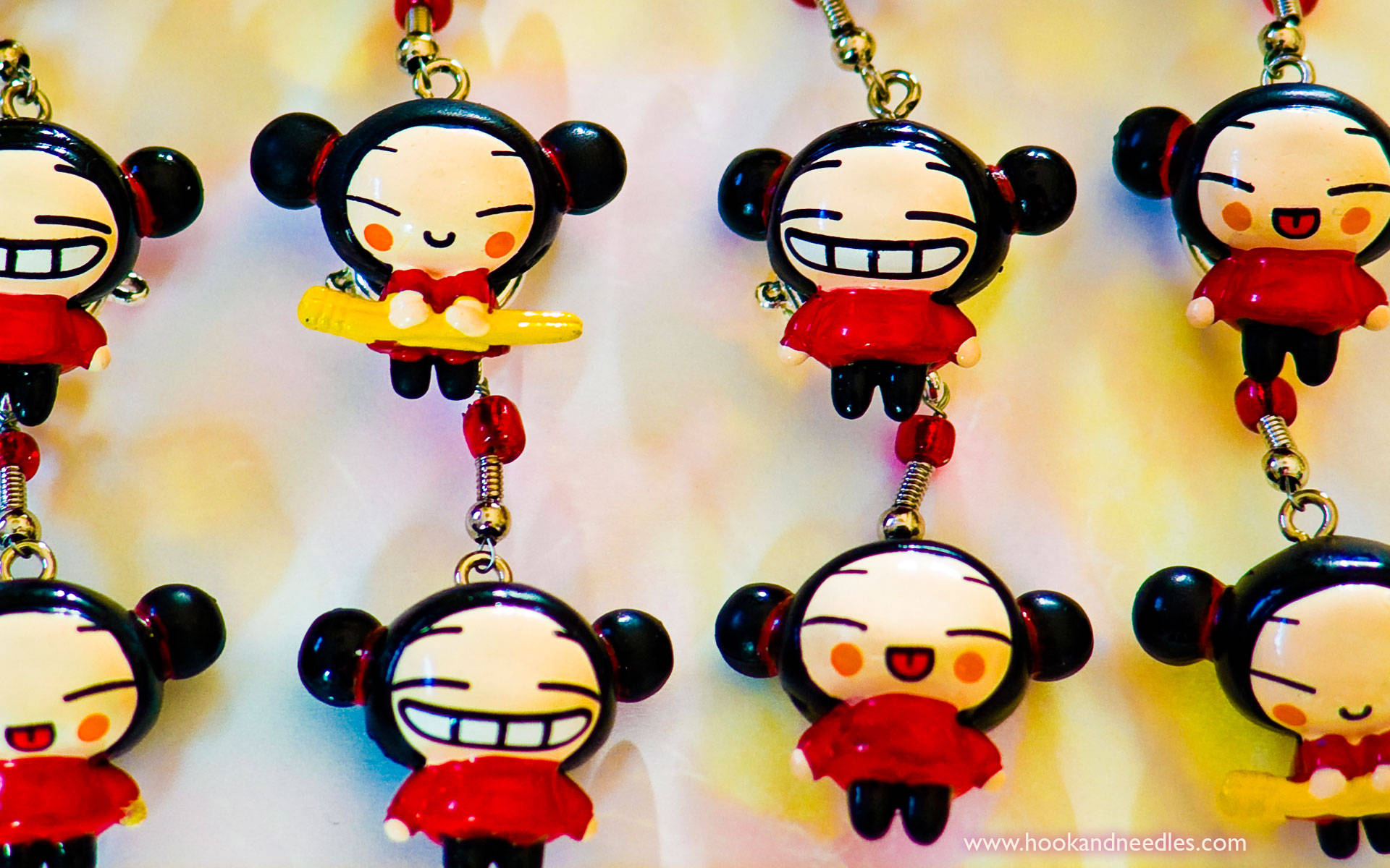 Pucca 桌布 壁紙 — 多個穿著紅色服裝、黑色頭髮的Pucca鑰匙圈掛在柔和黃色背景上的特寫。
