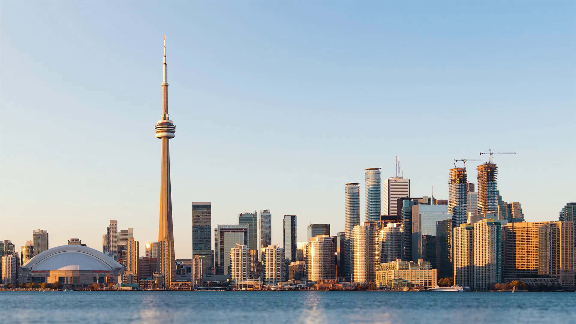 Toronto Skyline 桌布 壁紙 — 多倫多在黃金時段的天際線，CN塔和現代摩天大樓倒映在平靜的水面上。