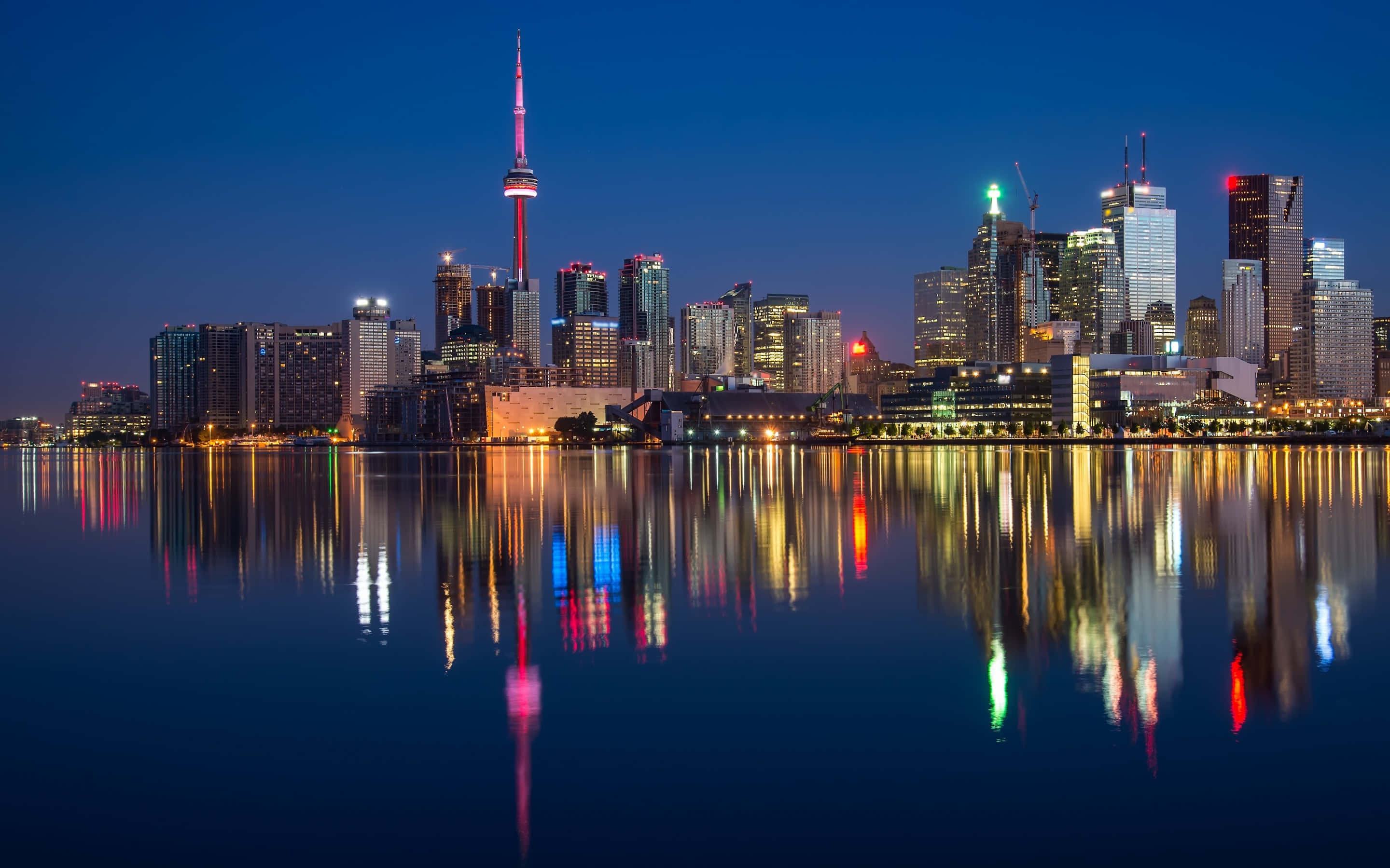 Toronto Skyline 桌布 壁紙 — 多倫多夜景，CN塔和摩天大樓在深藍色天空下倒映在平靜的水面上。