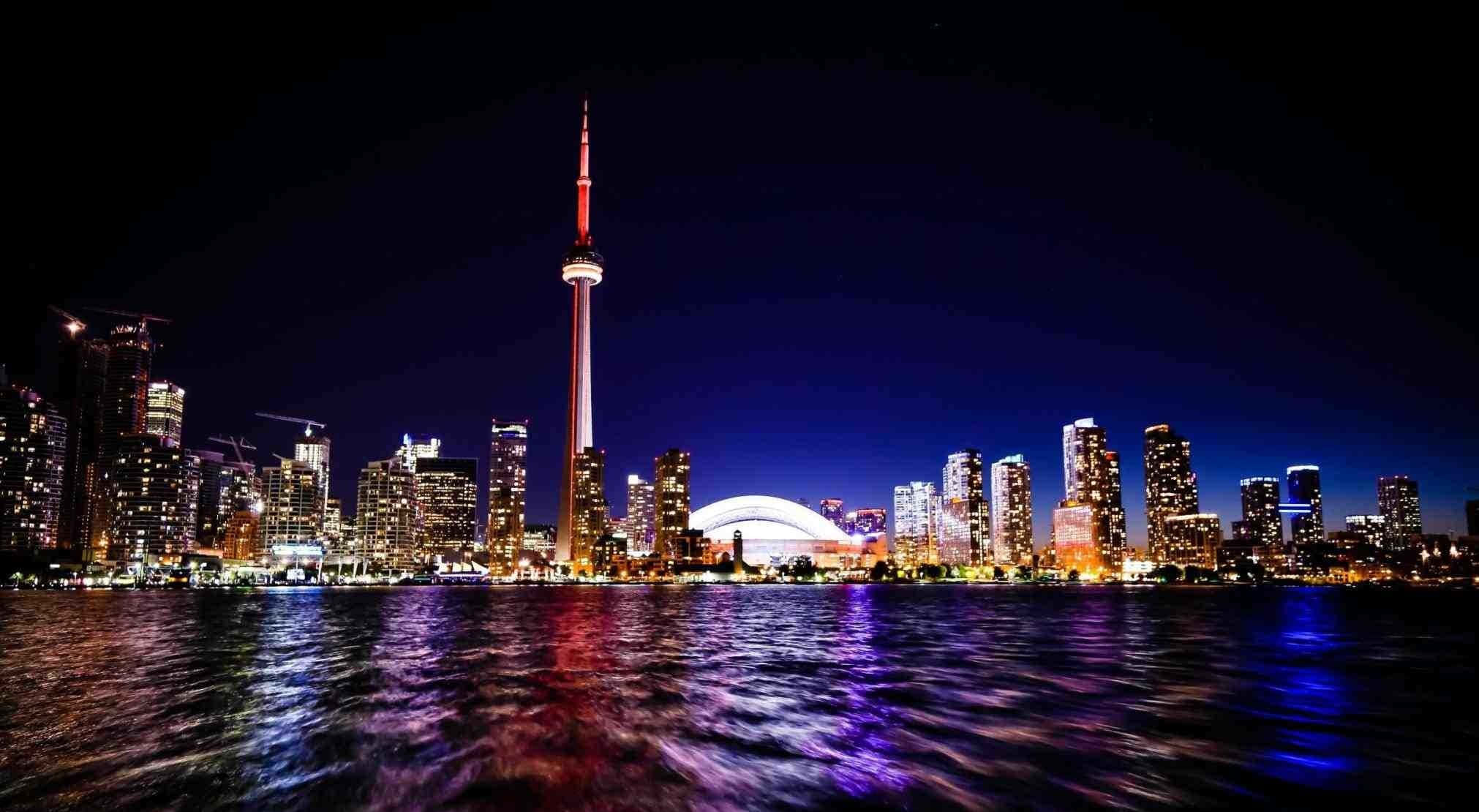 Toronto Skyline 桌布 壁紙 — 多倫多夜景天際線，CN塔發出紅光，城市燈光倒映在黑暗的水面上。