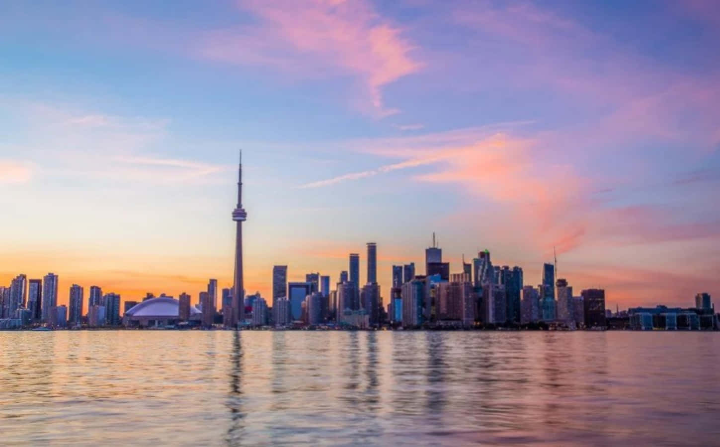 Toronto Skyline 桌布 壁紙 — 多倫多天際線在日落時分，CN塔倒映在平靜的水面上，天空呈現粉紅、橙色和藍色。