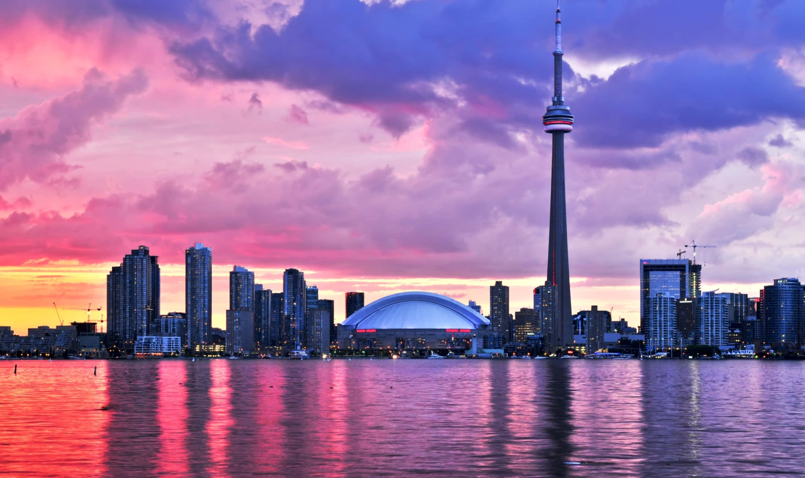 Toronto Skyline 桌布 壁紙 — 多倫多天際線在日落時分，CN塔和羅傑斯中心在粉紫色雲彩下倒映在水中。
