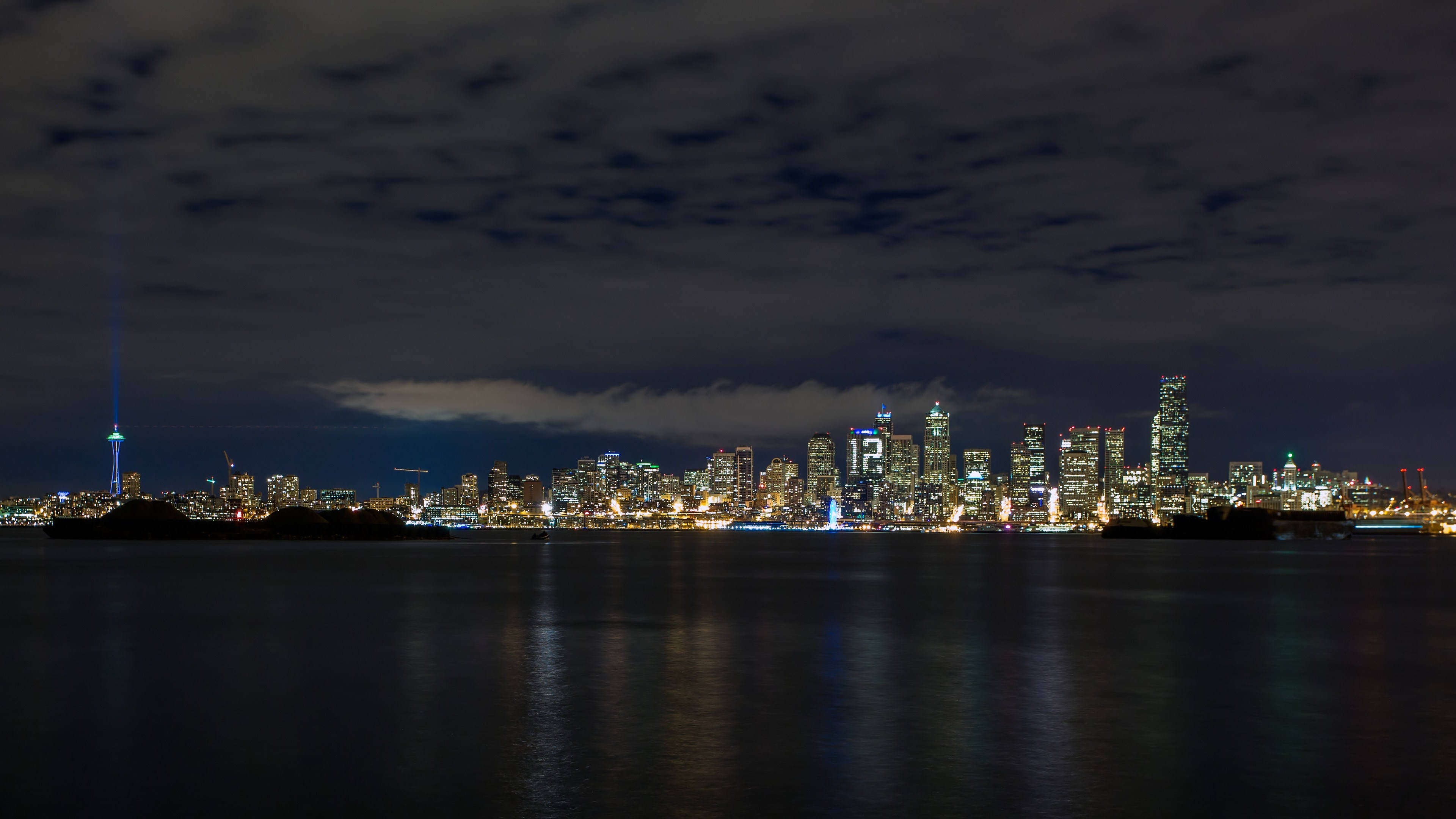 Seattle Skyline 桌布 壁紙 — 多倫多天際線的 panoramic 夜景，CN 塔閃耀，城市燈光在平靜的水面上反射，天空多雲。