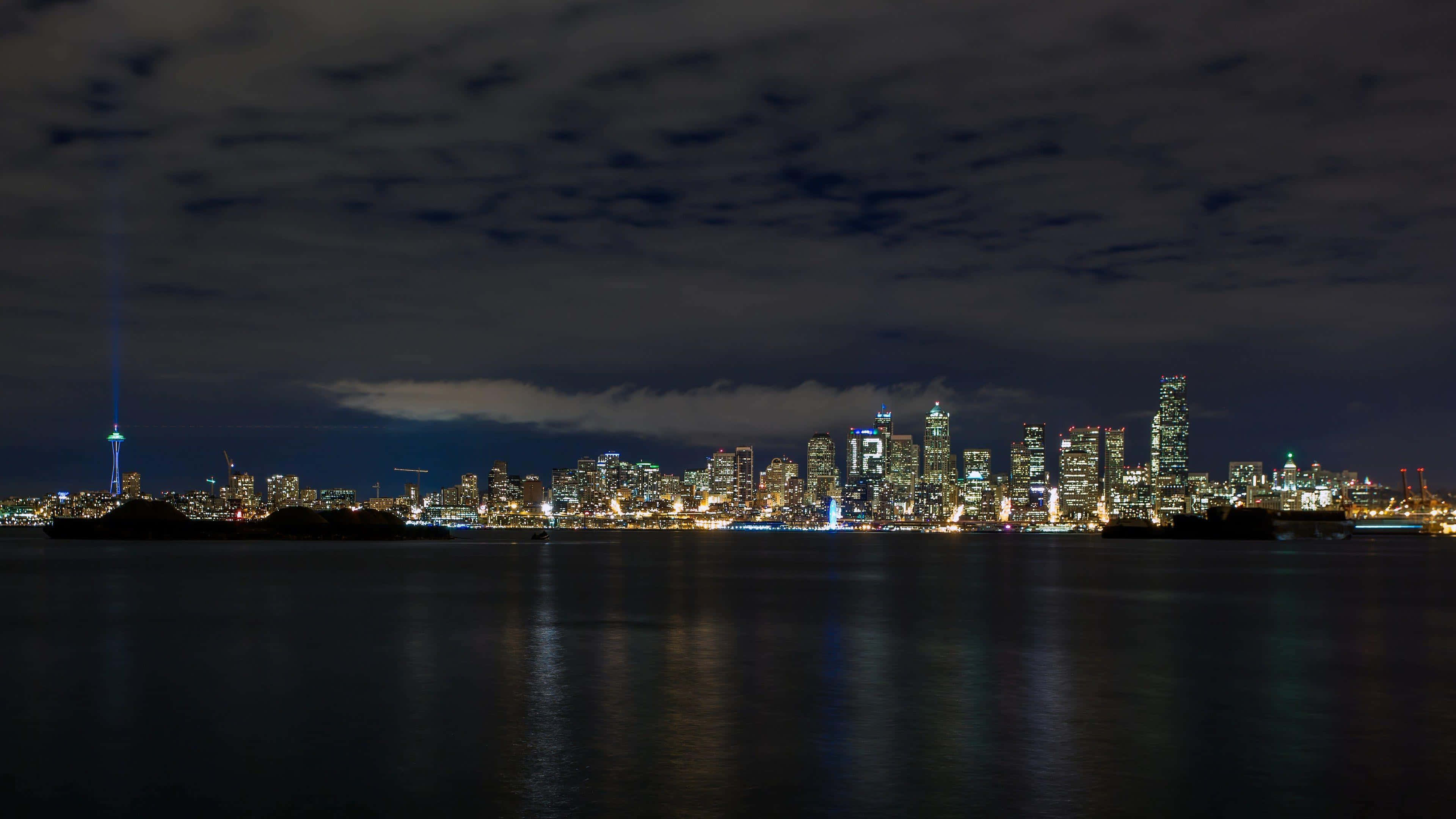 City At Night 桌布 壁紙 — 多倫多天際線的 panoramic 夜景，CN 塔閃爍，城市燈光在平靜的水面上反射，天空多雲。