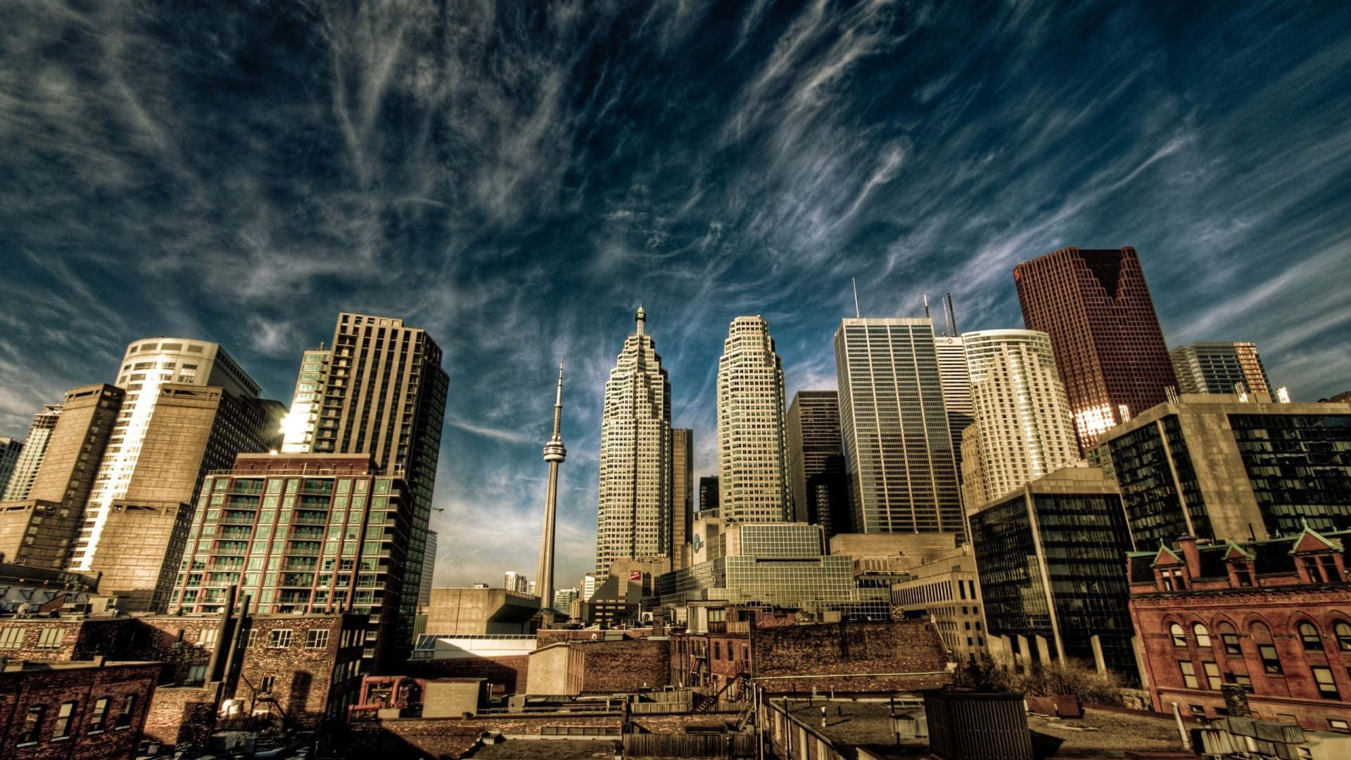 Toronto 桌布 壁紙 — 多倫多天際線的低角度戲劇性景觀，CN塔刺穿帶有縷縷雲彩的鮮豔藍天。