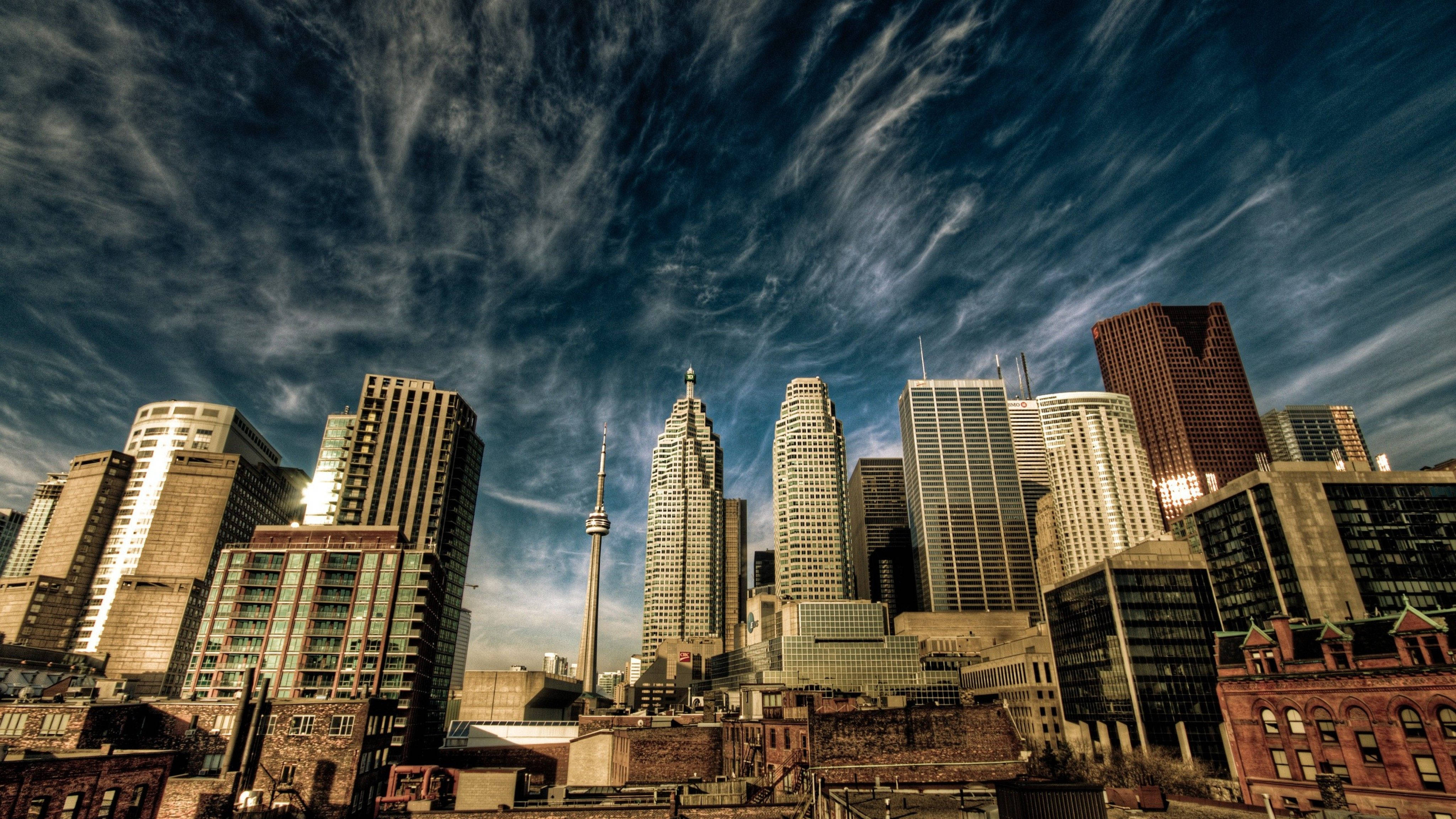 Toronto 桌布 壁紙 — 多倫多天際線的低角度戲劇性景觀，CN塔刺穿點綴著縷縷白雲的鮮豔藍天。