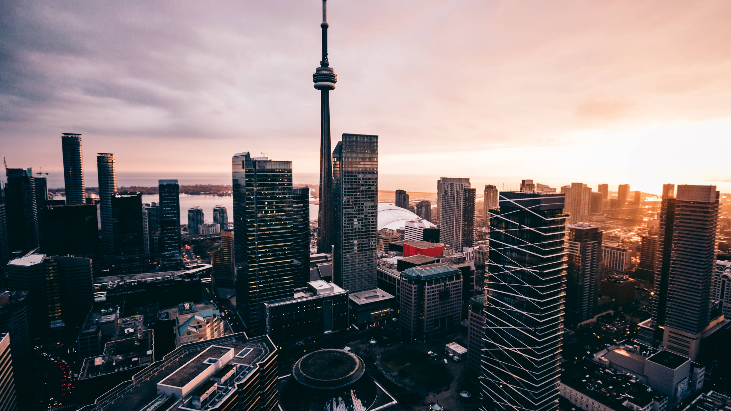 Toronto 桌布 壁紙 — 多倫多天際線的鳥瞰圖，日落時分，CN塔刺穿溫暖的橙色天空，下方是現代玻璃摩天大樓。