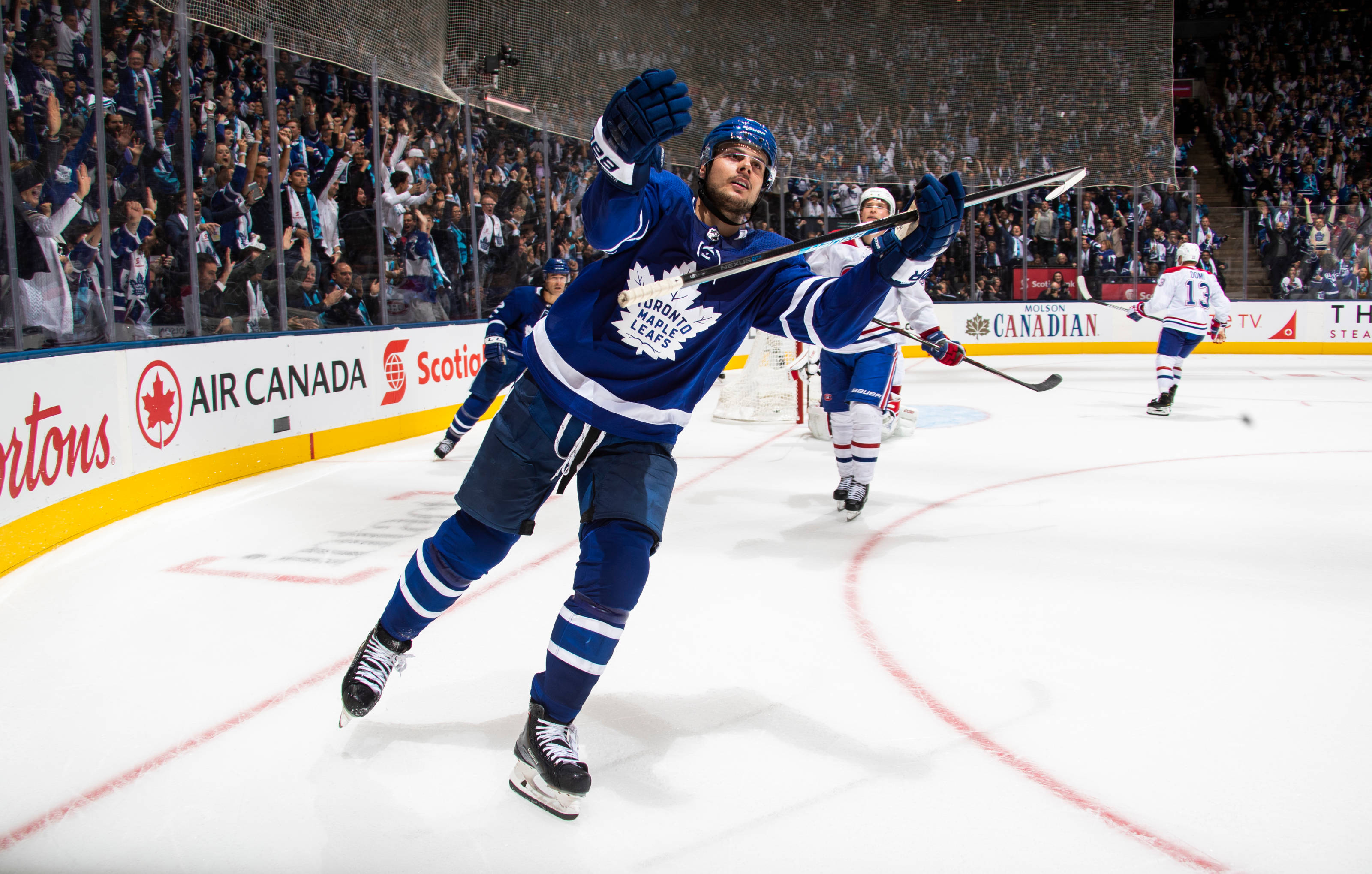 Leafs 桌布 壁紙 — 多倫多楓葉隊冰球球員在冰上高舉雙臂慶祝進球，背景有球迷歡呼。