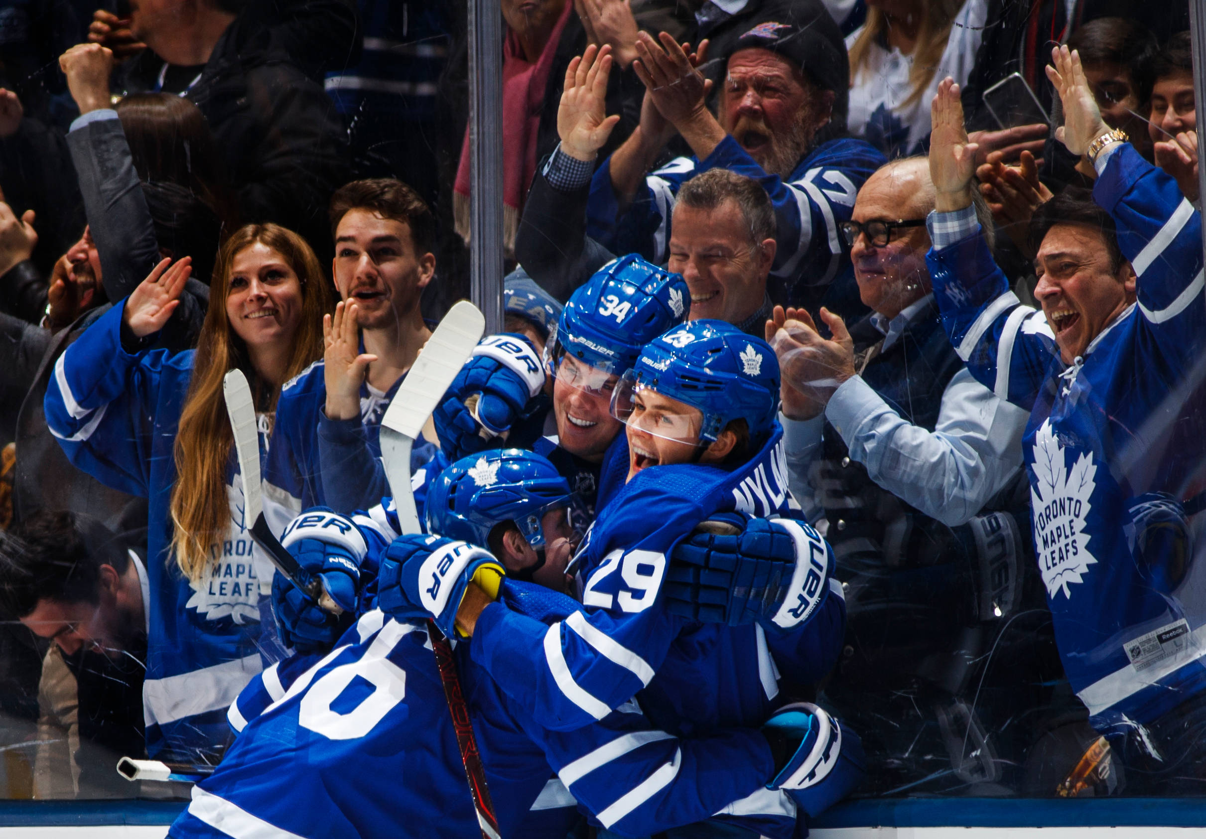 hockey 桌布 壁紙 — 多倫多楓葉隊的冰球球員身穿藍色球衣，在玻璃後球迷的歡呼聲中慶祝進球。
