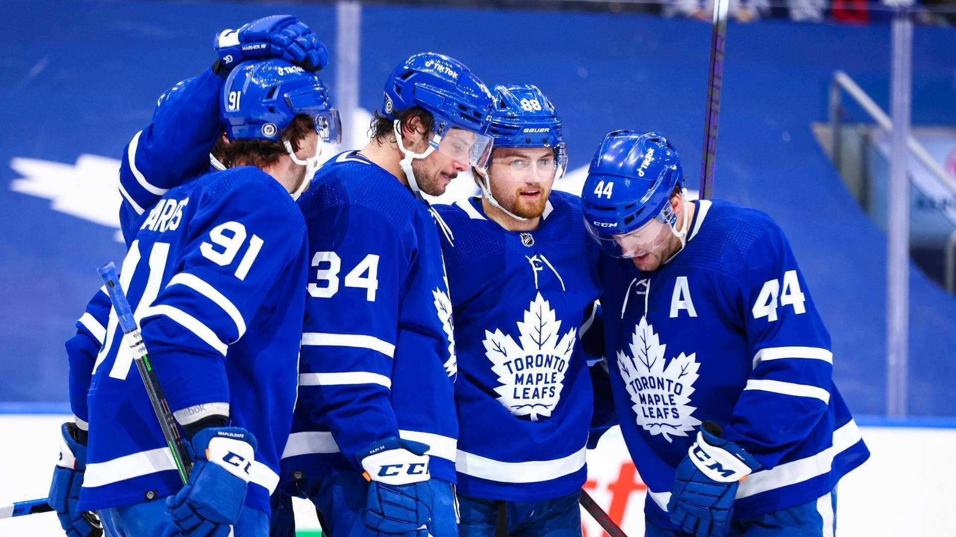 Leafs 桌布 壁紙 — 多倫多楓葉隊的冰球運動員穿著藍色球衣在比賽中緊密聚集在冰上。