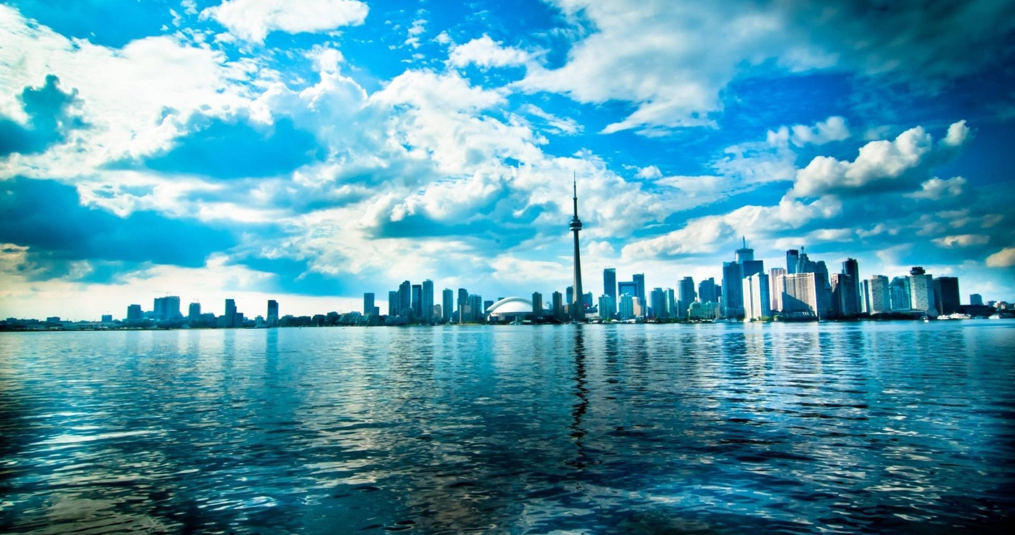 Toronto 桌布 壁紙 — 多倫多標誌性天際線（包括CN塔）前平靜的水面反射出帶有蓬鬆雲朵的鮮豔藍天。