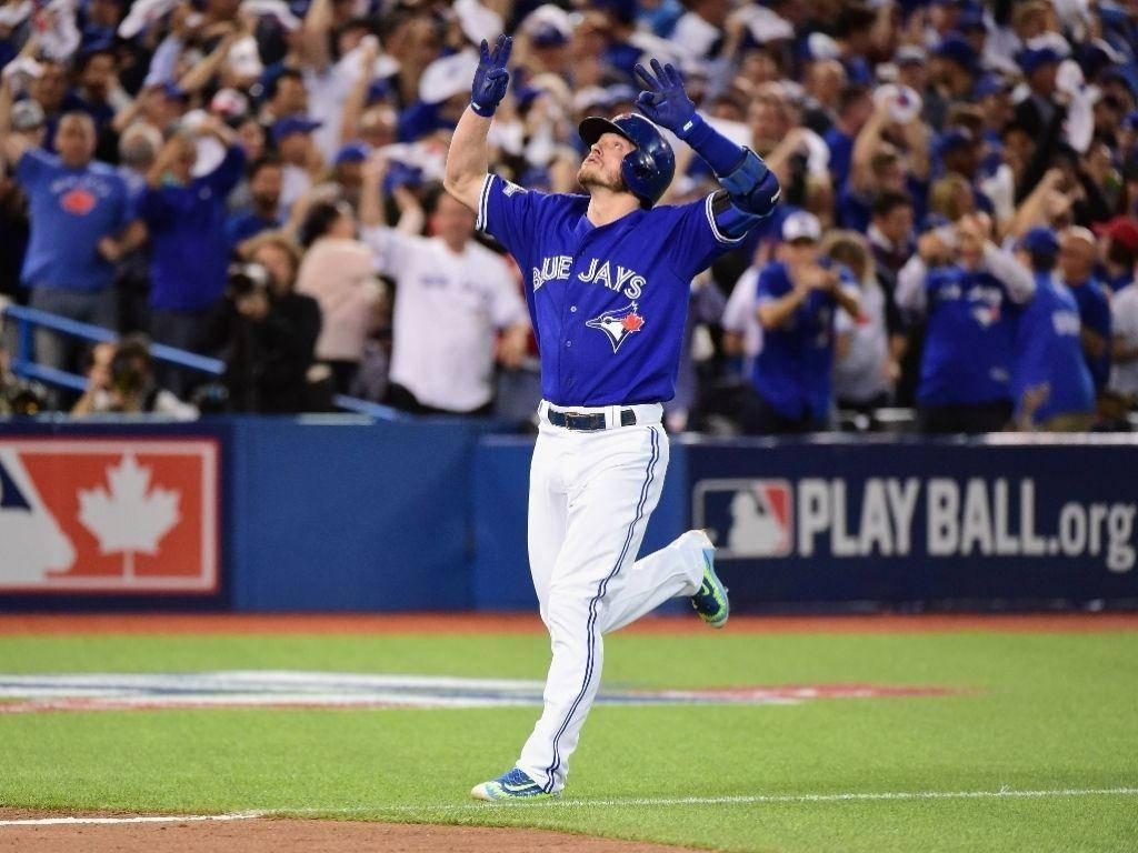 MLB 桌布 壁紙 — 多倫多藍鳥隊棒球選手在體育場燈光下，於充滿活力的綠色球場上高舉雙臂慶祝勝利。