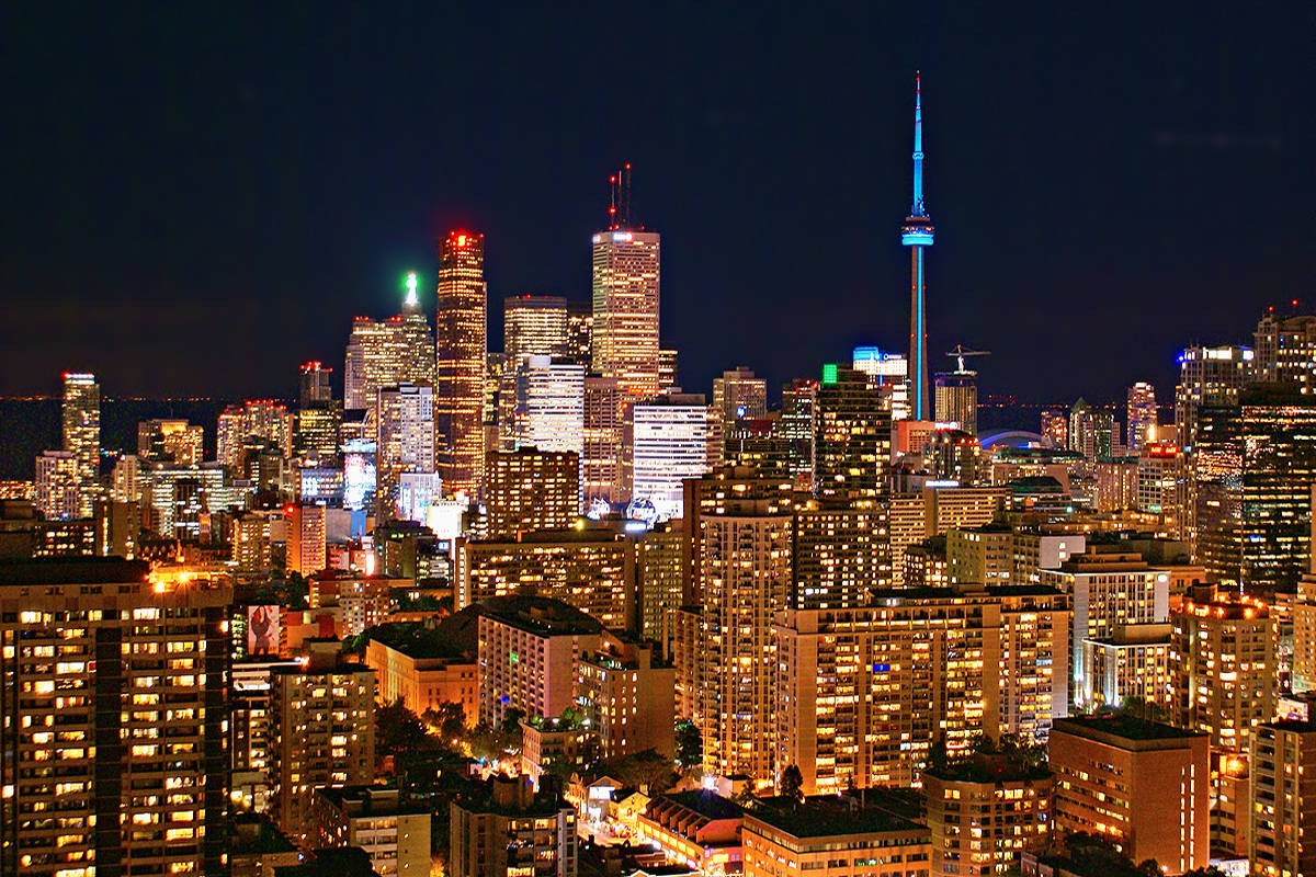 Ontario 桌布 壁紙 — 多倫多迷人的夜景，CN塔閃耀藍光，摩天大樓在黑暗的天空中散發溫暖的金色光芒。