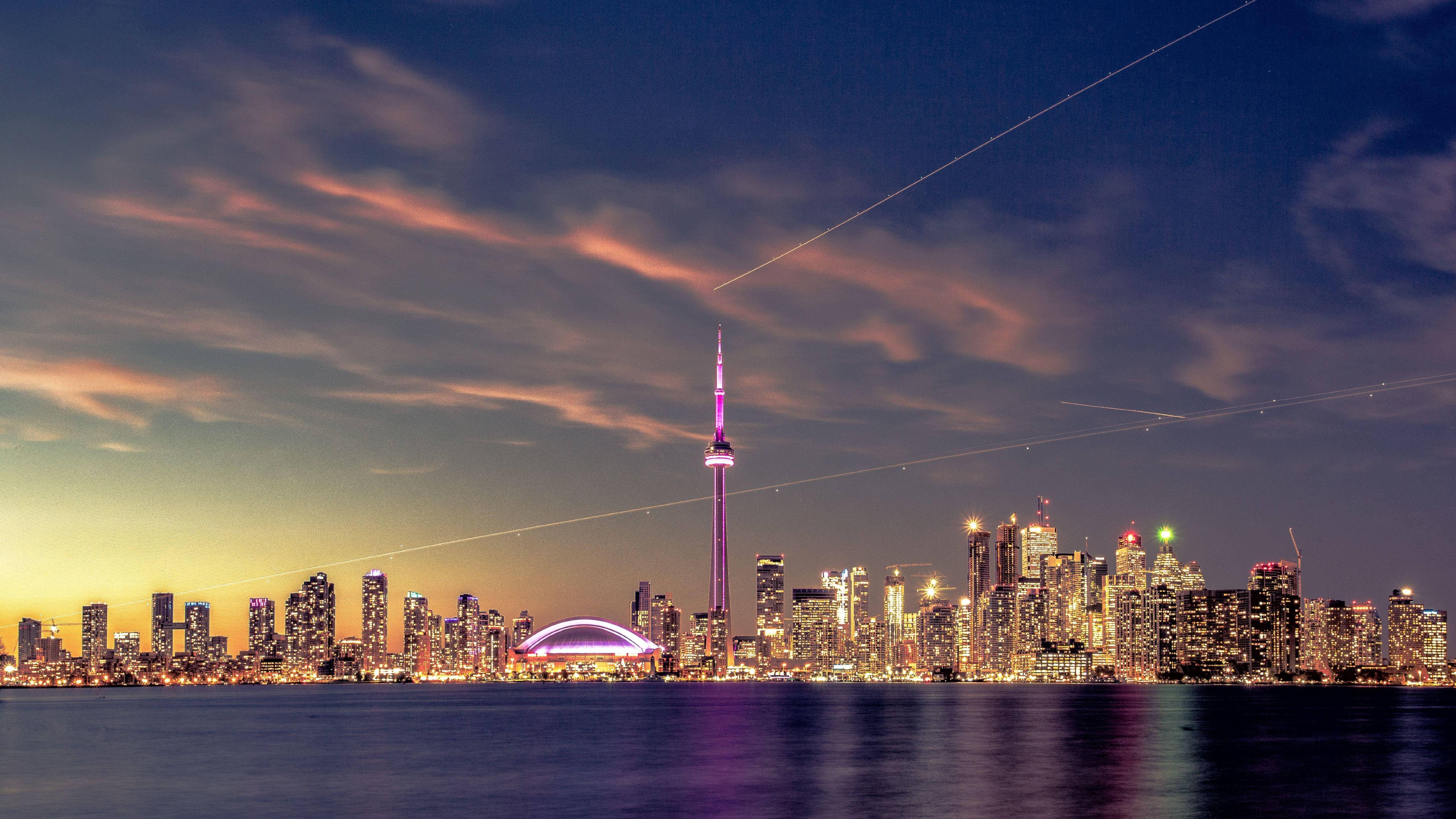 Ontario 桌布 壁紙 — 多倫多黃昏天際線，CN塔亮起紫色燈光，城市燈光在條紋雲下倒映在水面上。
