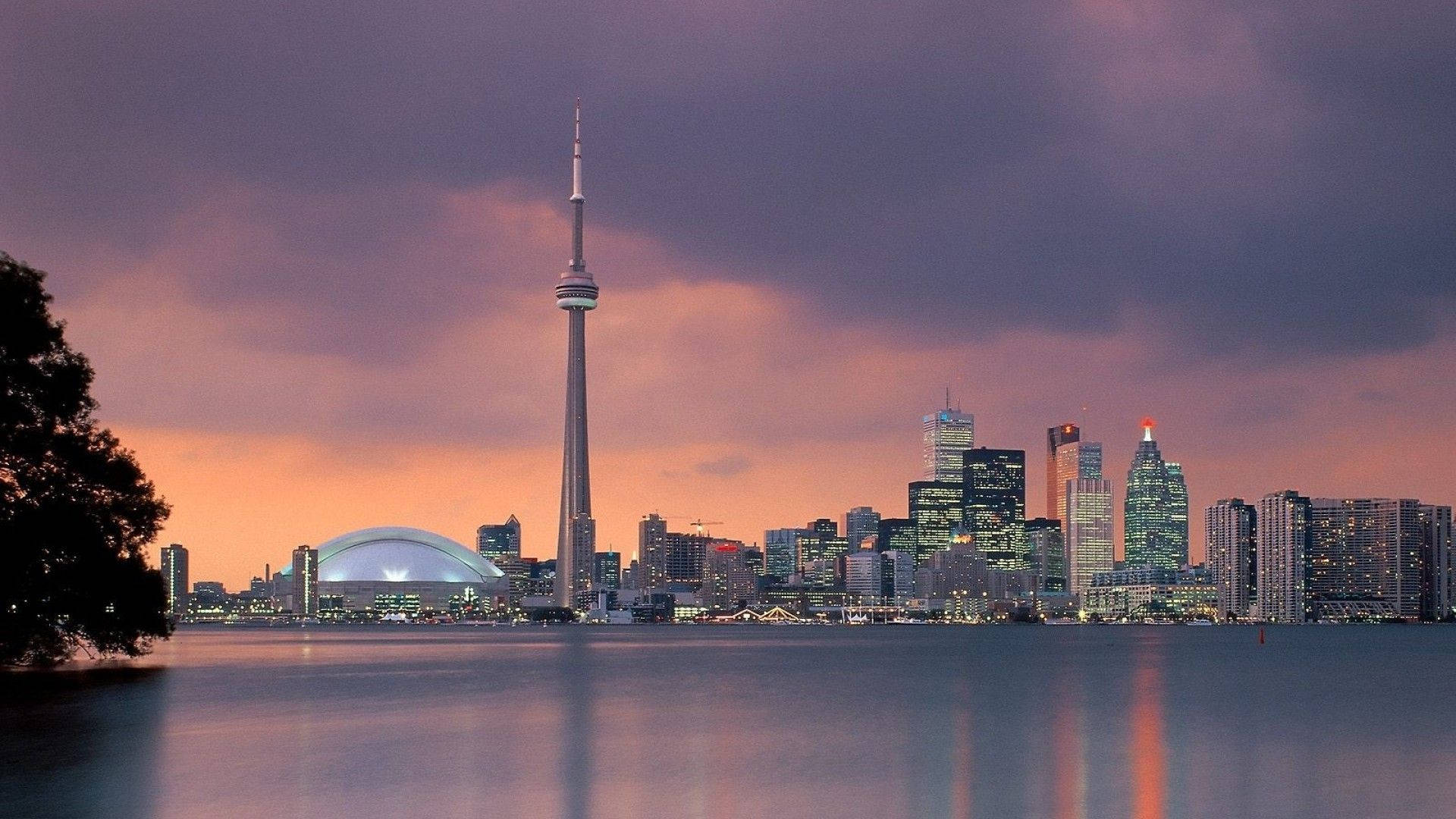 Toronto 桌布 壁紙 — 多倫多黃昏天際線，CN塔和摩天大樓在紫色橙色雲層下的平靜水面中倒映。