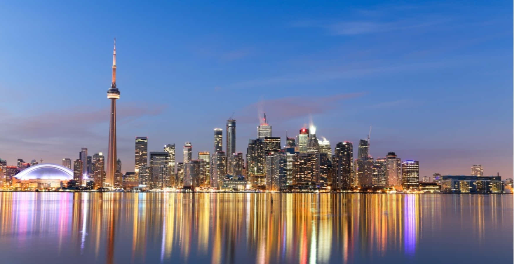 Toronto Skyline 桌布 壁紙 — 多倫多黃昏天際線，CN塔和摩天大樓在漸變藍天下倒映在平靜的水面上。