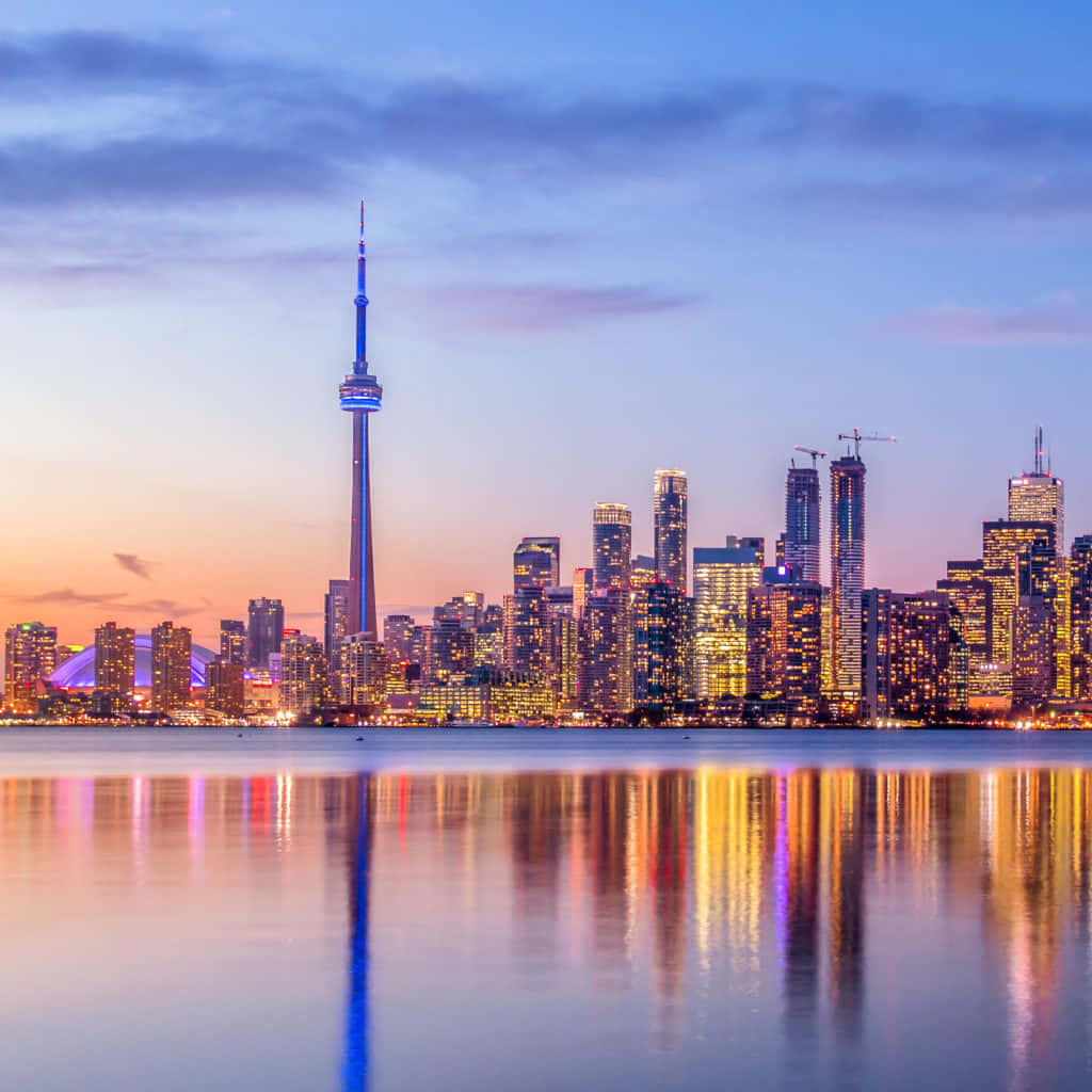Toronto Skyline 桌布 壁紙 — 多倫多黃昏天際線，CN塔和摩天大樓在平靜的水面上倒映，天空呈現紫橙色。