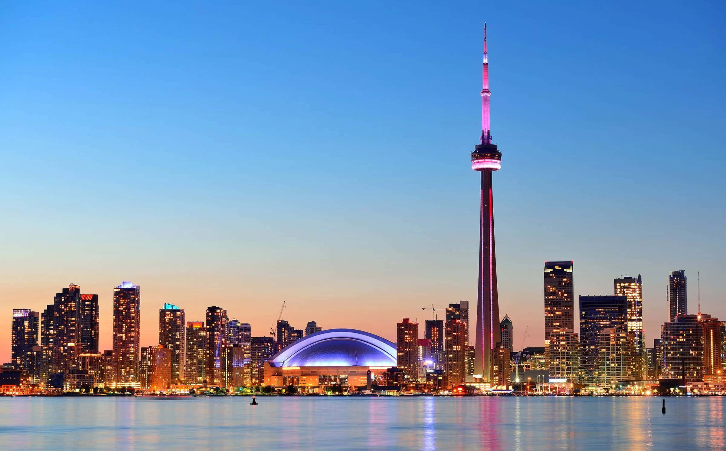 Toronto 桌布 壁紙 — 多倫多黃昏天際線，CN塔在粉紅和藍色中發光，水面倒映城市燈光。