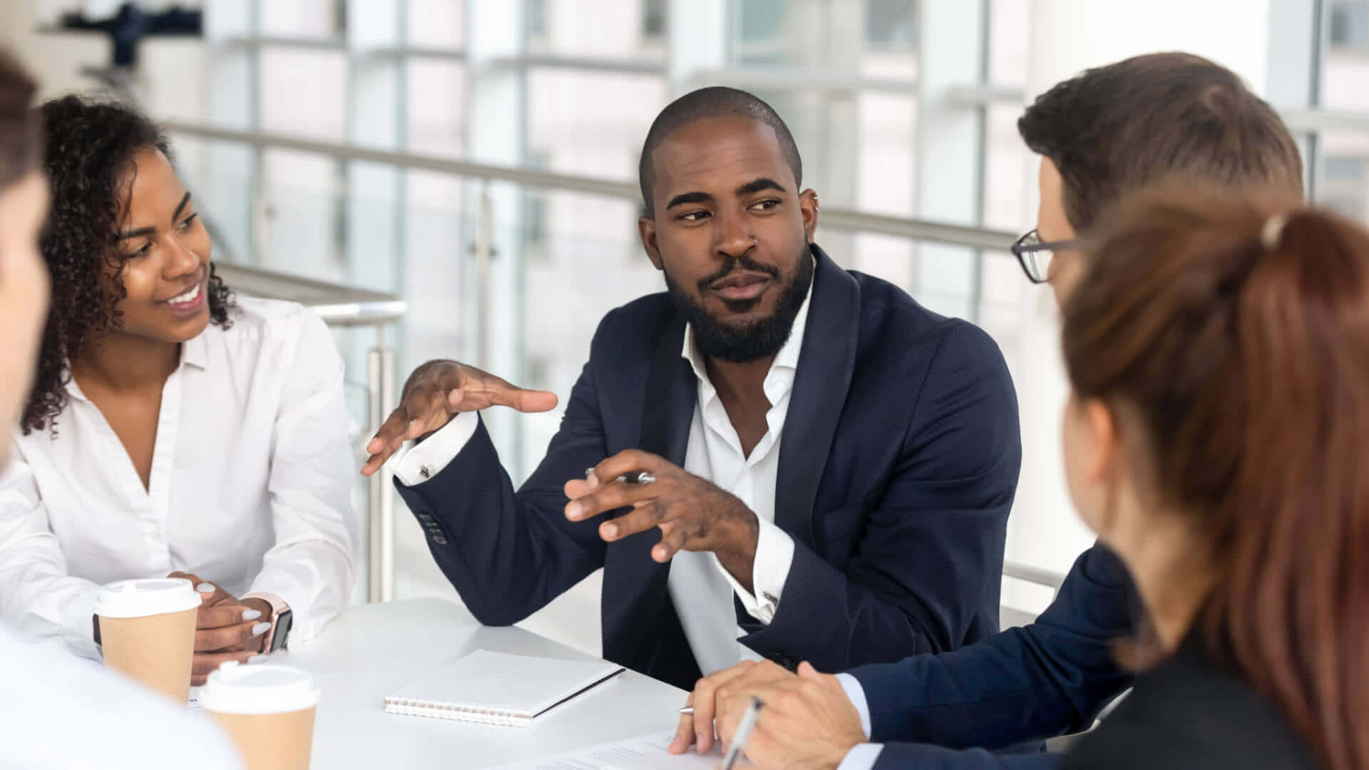 Leadership 桌布 壁紙 — 多元化的商業團隊圍繞現代玻璃牆會議桌進行專注的會議。