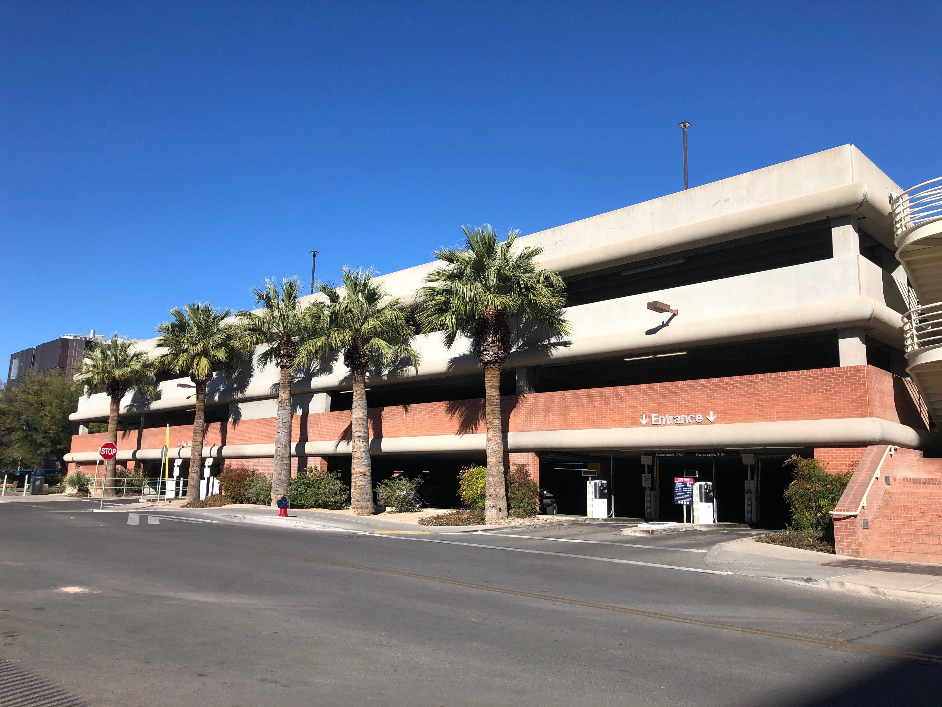 Arizona 桌布 壁紙 — 多層混凝土停車場，帶有磚塊裝飾和棕櫚樹，在清澈的藍天下。