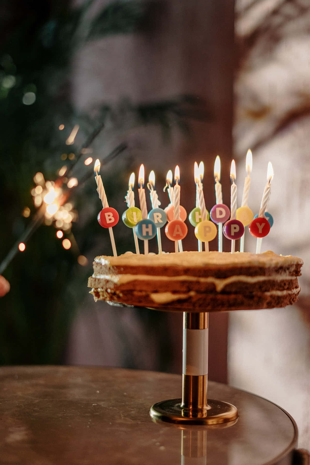 生日快樂 桌布 壁紙 — 多層生日蛋糕，上面有彩色字母蠟燭拼出 'HAPPY BIRTHDAY'，背景有閃爍的煙火棒。