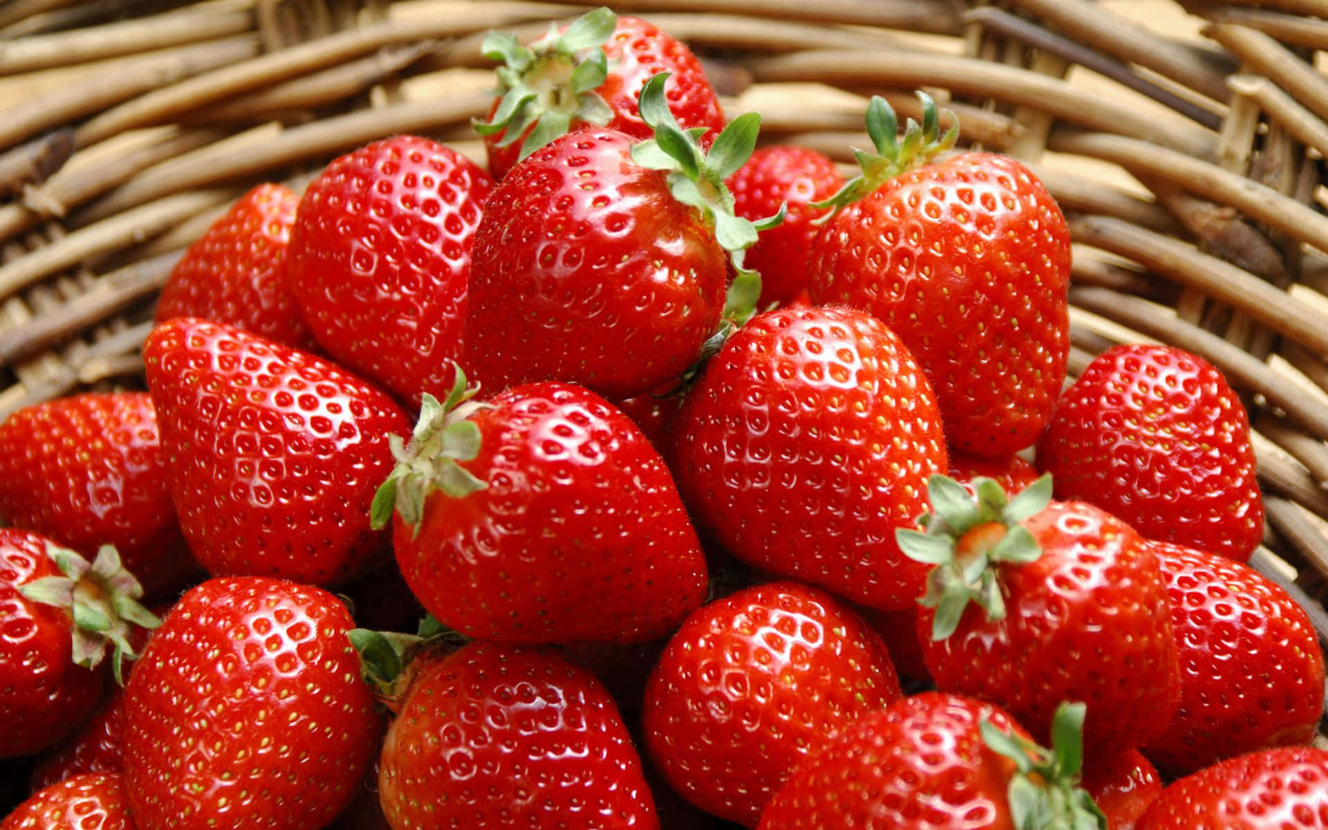 Cute Strawberry 桌布 壁紙 — 多汁成熟的草莓，帶綠色頂部，堆放在編織籃中。