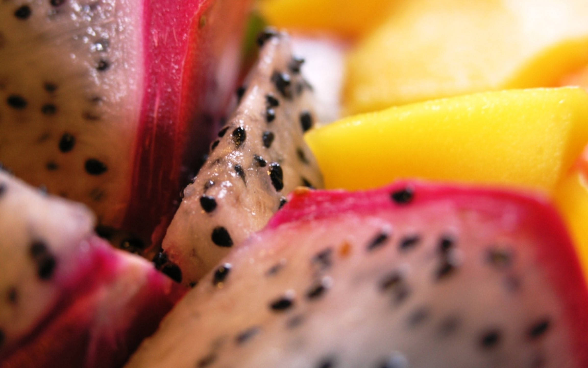 Fruit 桌布 壁紙 — 多汁火龍果切片帶黑色籽，旁邊是鮮黃色芒果塊的特寫。