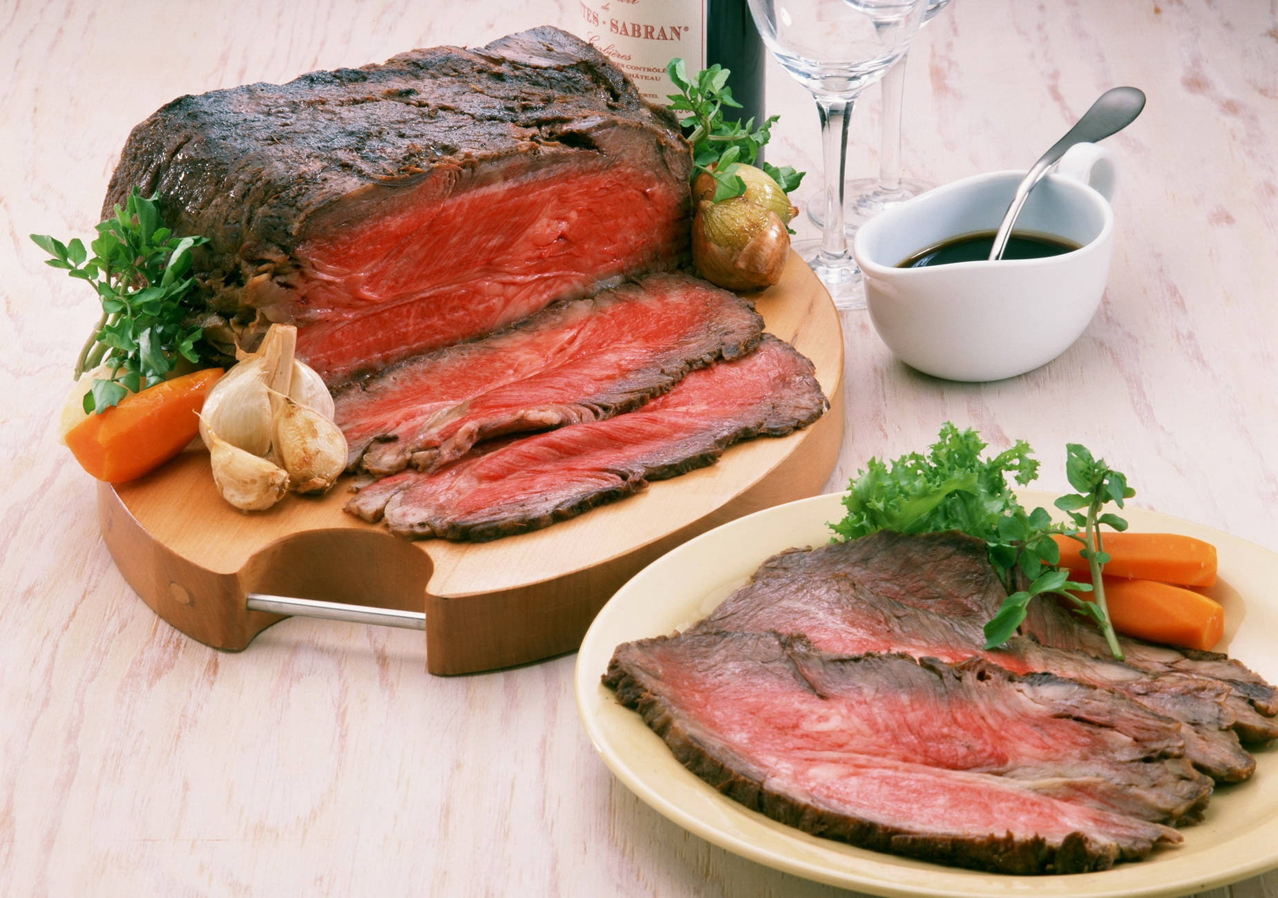 meat 桌布 壁紙 — 多汁烤牛胸肉，中心呈粉紅色，切片放在木砧板和盤子上，以歐芹、紅蘿蔔和大蒜裝飾。