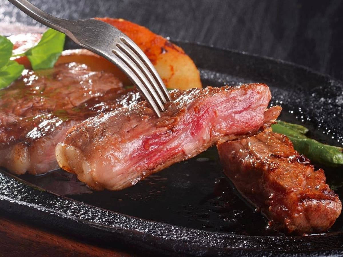 meat 桌布 壁紙 — 多汁的 medium-rare 牛排用叉子切開，配上烤馬鈴薯和蘆筍，放在黑色石盤上。