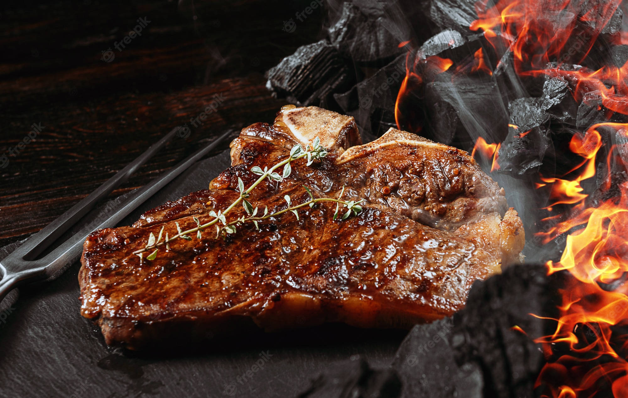 meat 桌布 壁紙 — 多汁的T骨牛排熾熱的炭火上滋滋作響，配上新鮮百里香，置於深色石面上。