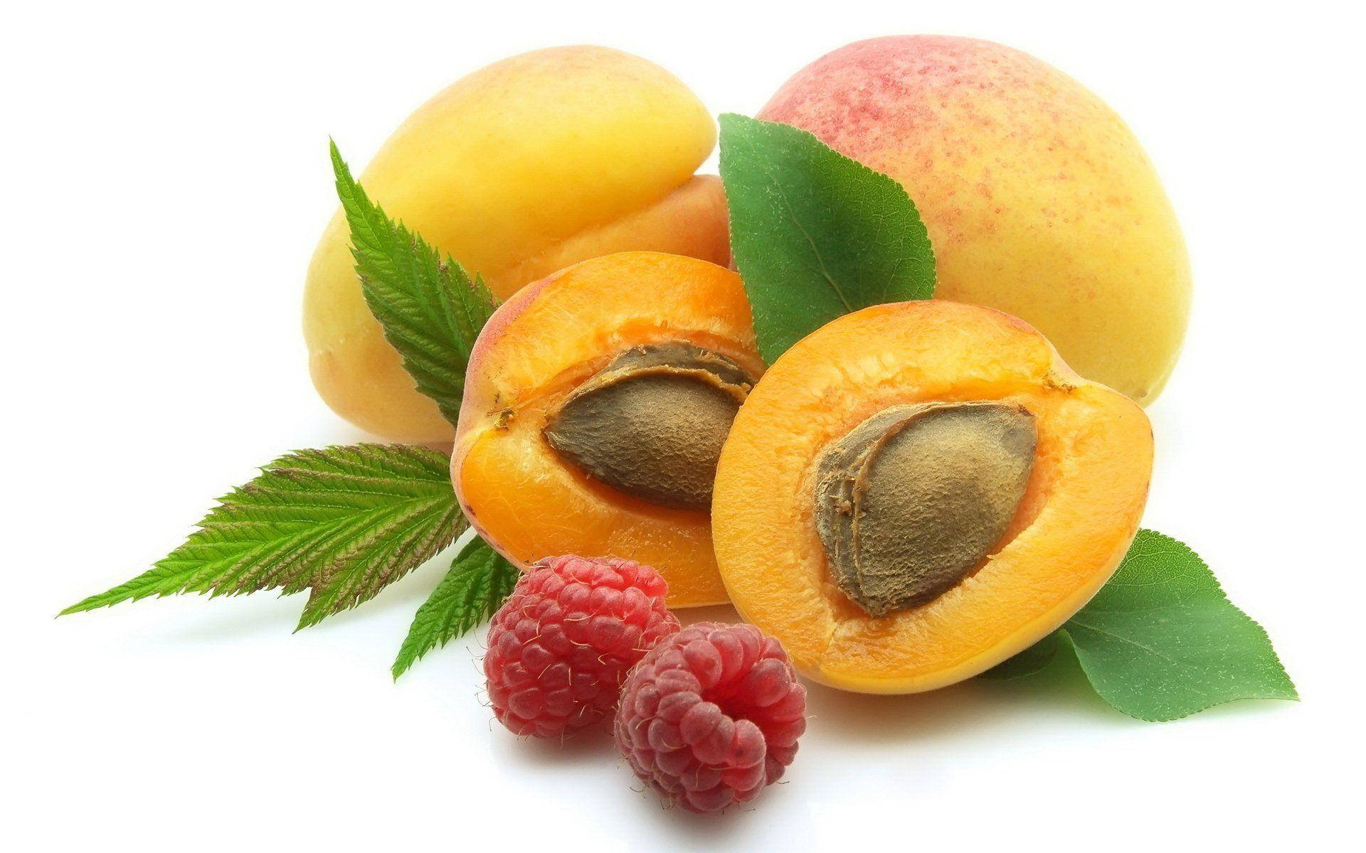 Fruits 桌布 壁紙 — 多汁的杏子和覆盆子，搭配綠葉，排列在潔淨的白色背景上。