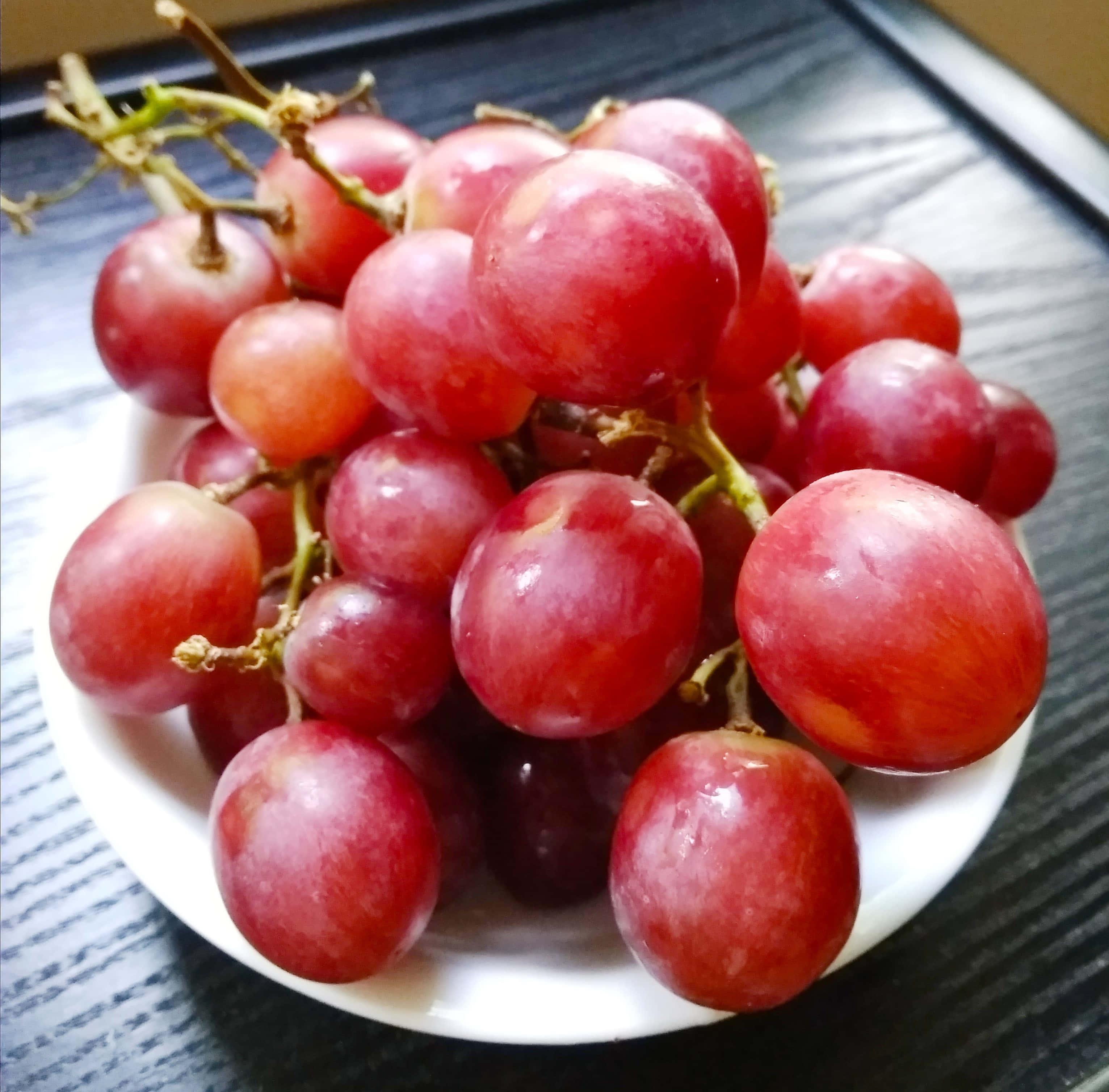 Grape 桌布 壁紙 — 多汁的紅葡萄在深色木桌上的白色盤子上閃閃發光。