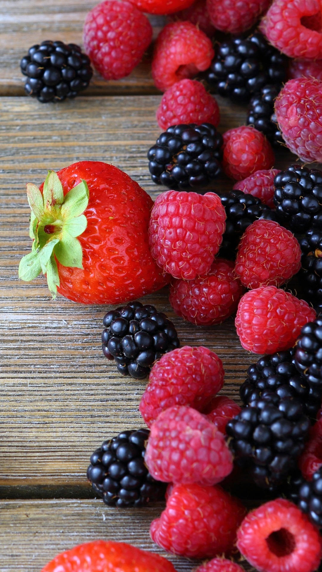 Strawberry 桌布 壁紙 — 多汁的草莓、覆盆子和黑莓散落在質樸的木質表面上。