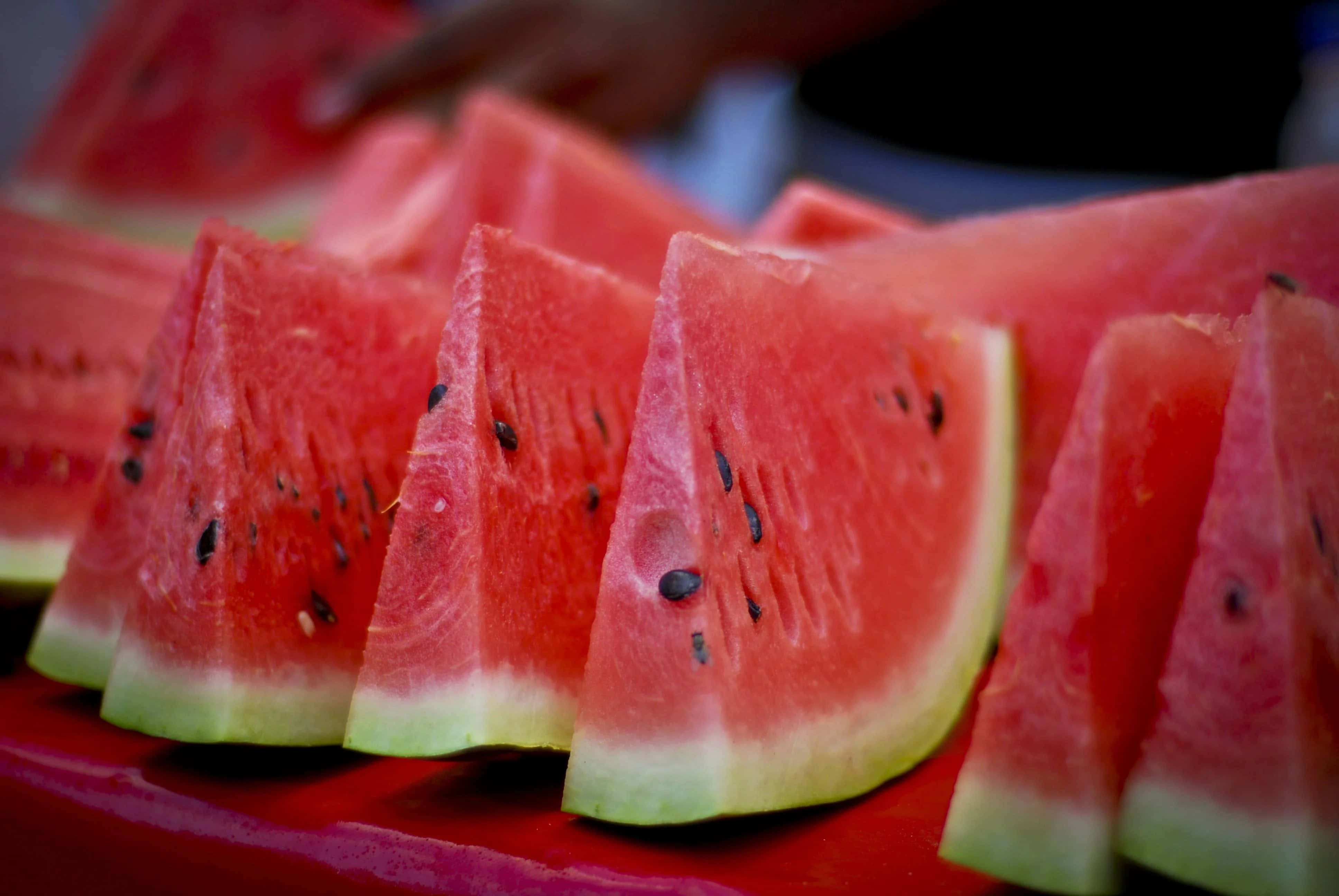 Watermelon 桌布 壁紙 — 多汁的西瓜片，帶有黑色種子，排列在鮮紅色的表面上。
