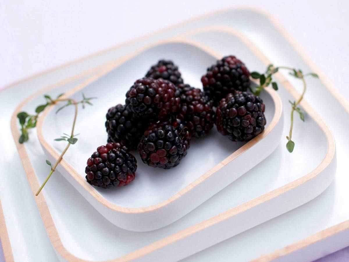 Berry 桌布 壁紙 — 多汁的黑莓和新鮮百里香枝條放在帶木邊的白色陶瓷托盤上。
