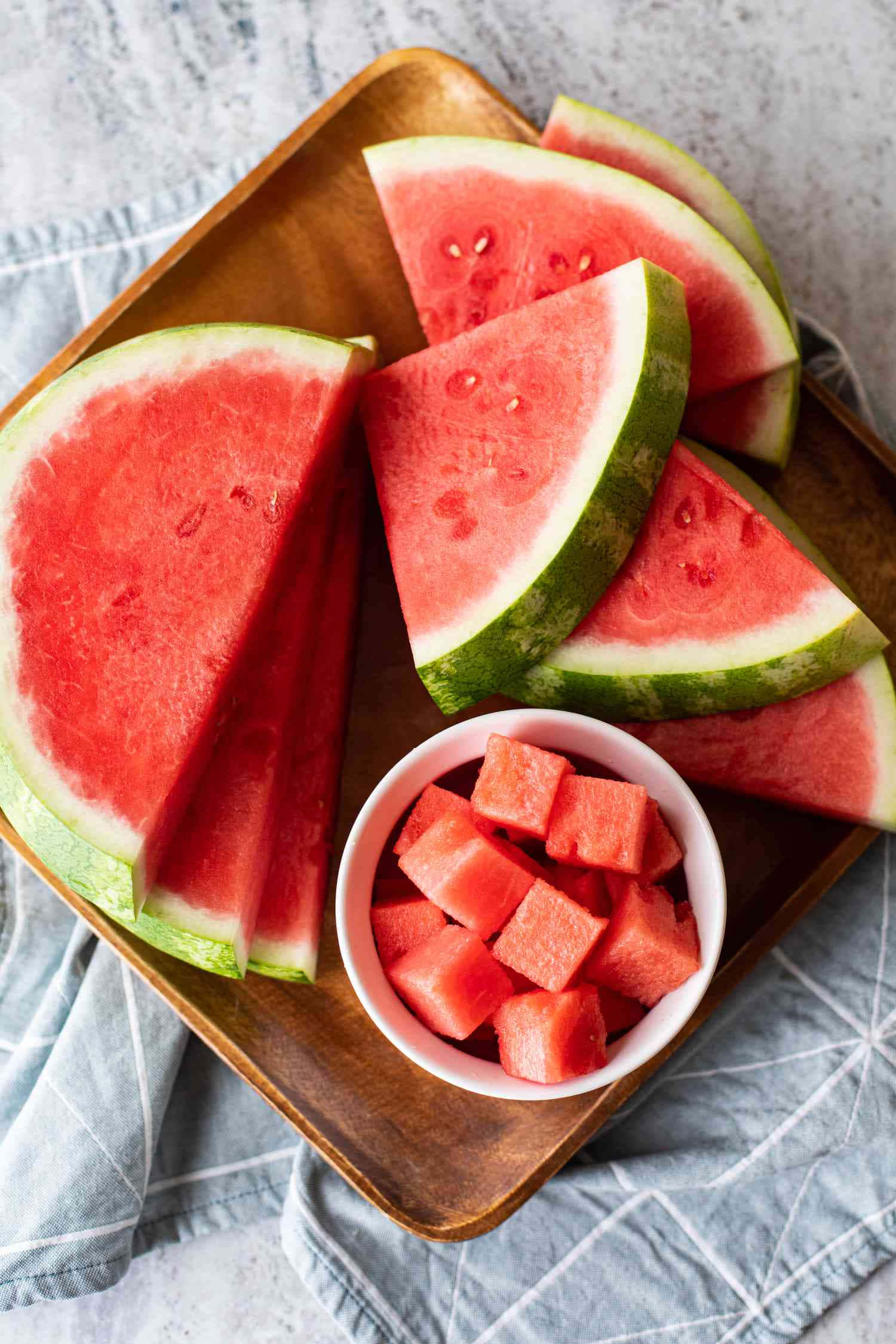 Watermelon 桌布 壁紙 — 多汁西瓜片和方塊排列在木托盤上，置於藍色條紋布上。