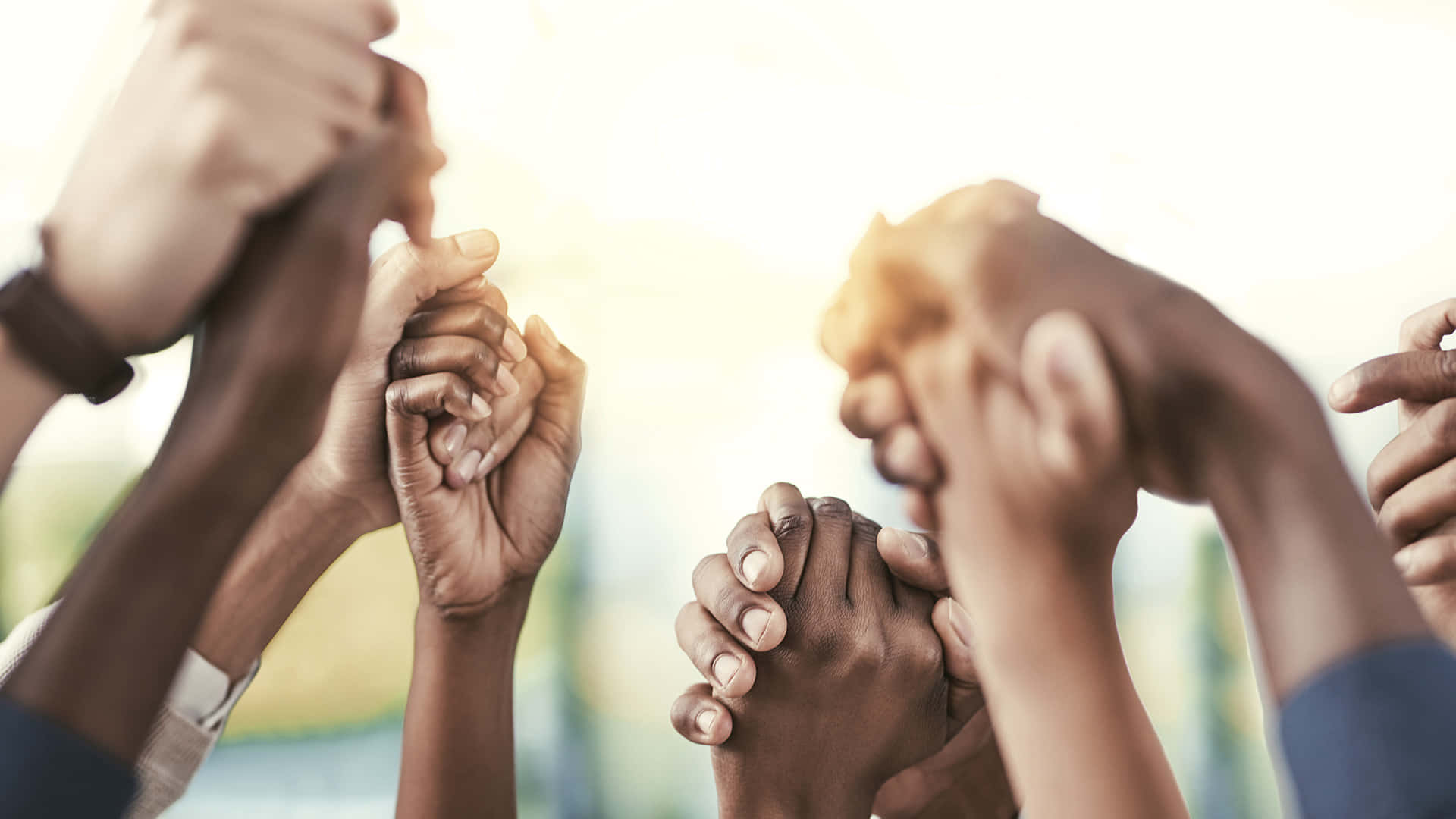 Racism 桌布 壁紙 — 多種不同的手緊握在一起，團結一致，背景明亮模糊。