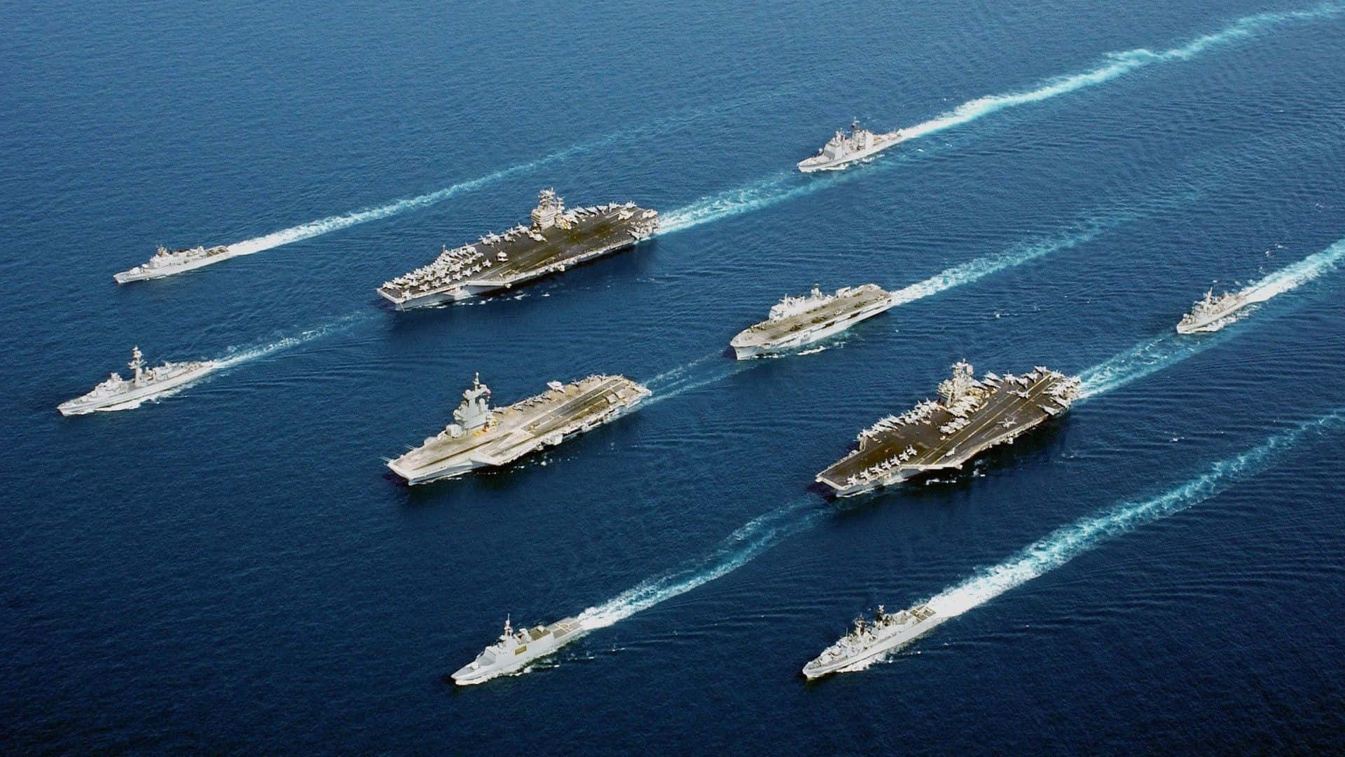 Navy 桌布 壁紙 — 多艘航空母艦及護航艦在深藍色海洋上編隊航行的鳥瞰圖。