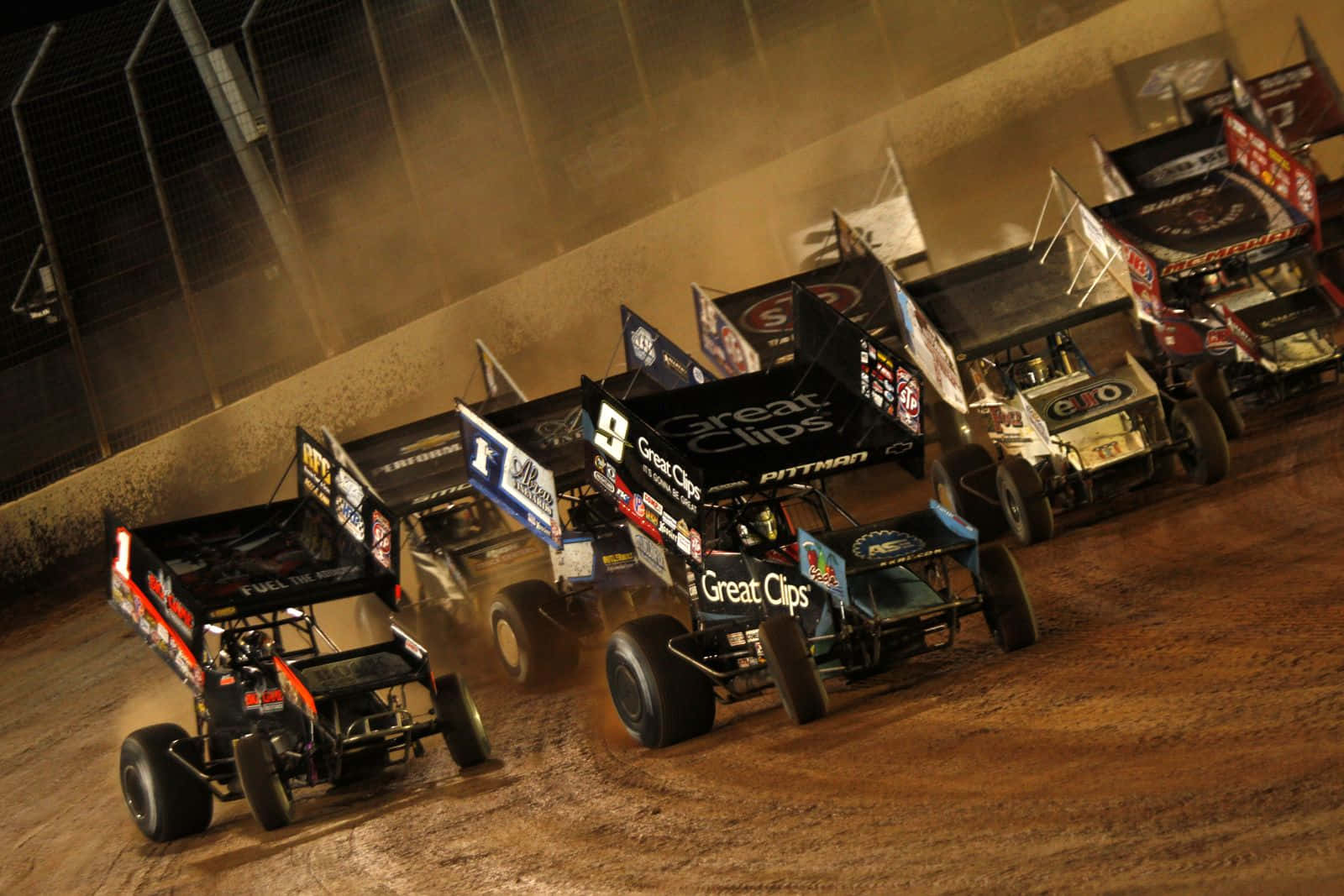 Sprint Car Racing 桌布 壁紙 — 多輛改裝量產車在緊湊比賽中揚起塵土的壯觀夜間泥地賽道比賽。