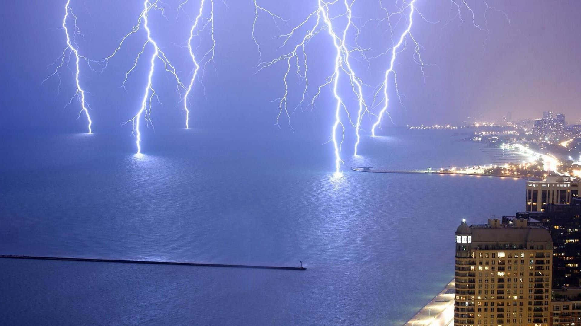 thunder 桌布 壁紙 — 多道明亮的閃電劃過夜間城市天際線附近的黑暗水域。