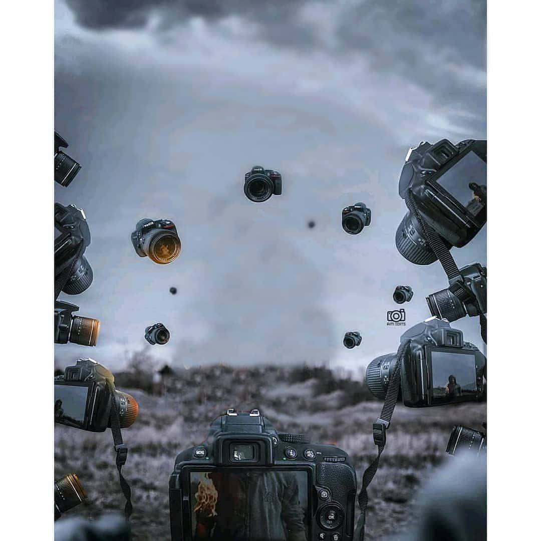 Dslr Camera 桌布 壁紙 — 多部DSLR相機漂浮在暴風雨的天空中，下方是荒蕪的田野，前景中的一部相機顯示出一個人的倒影。